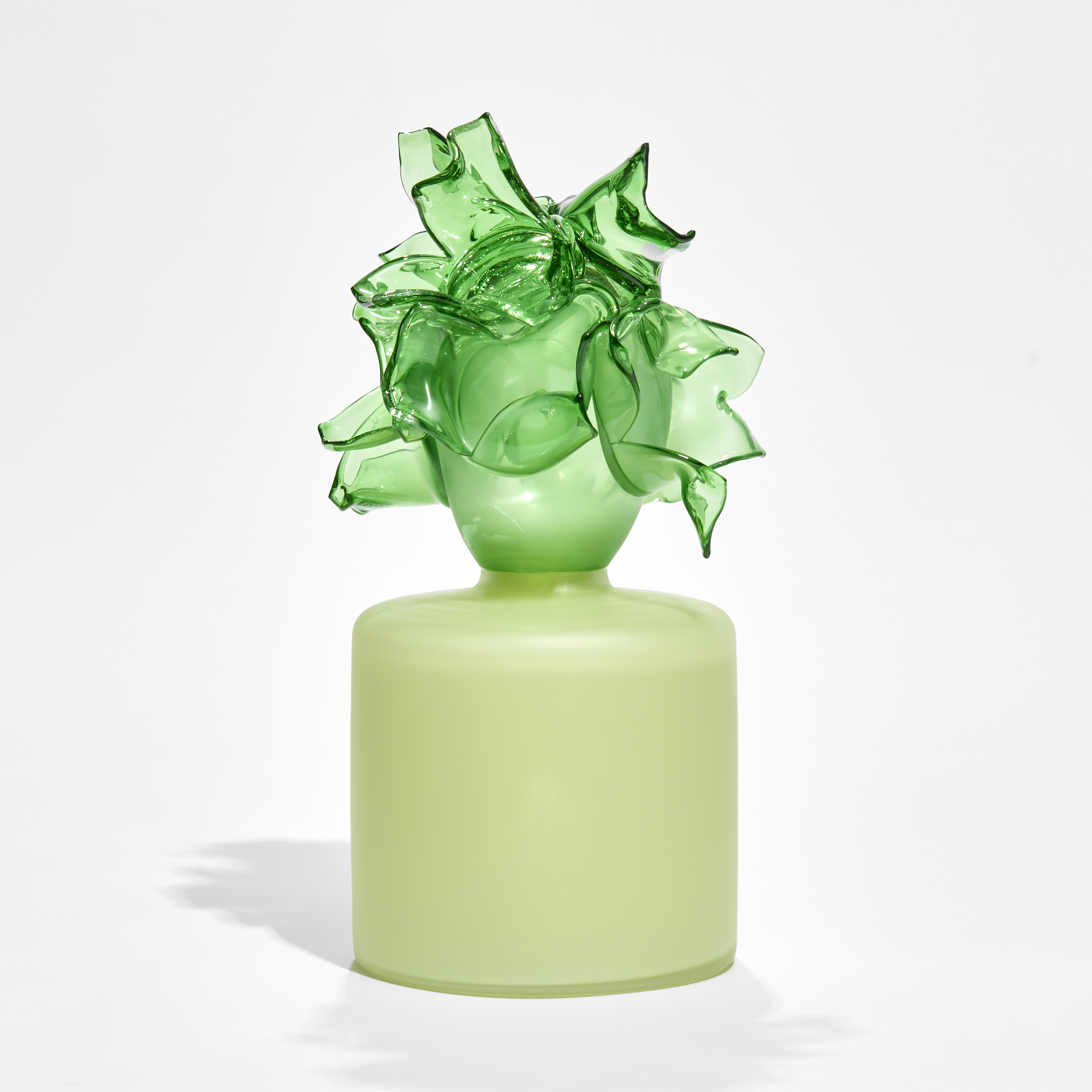 round soft green box with bright green abstract floral adornment on the top hand made from glass 