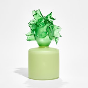 round soft green box with bright green abstract floral adornment on the top hand made from glass