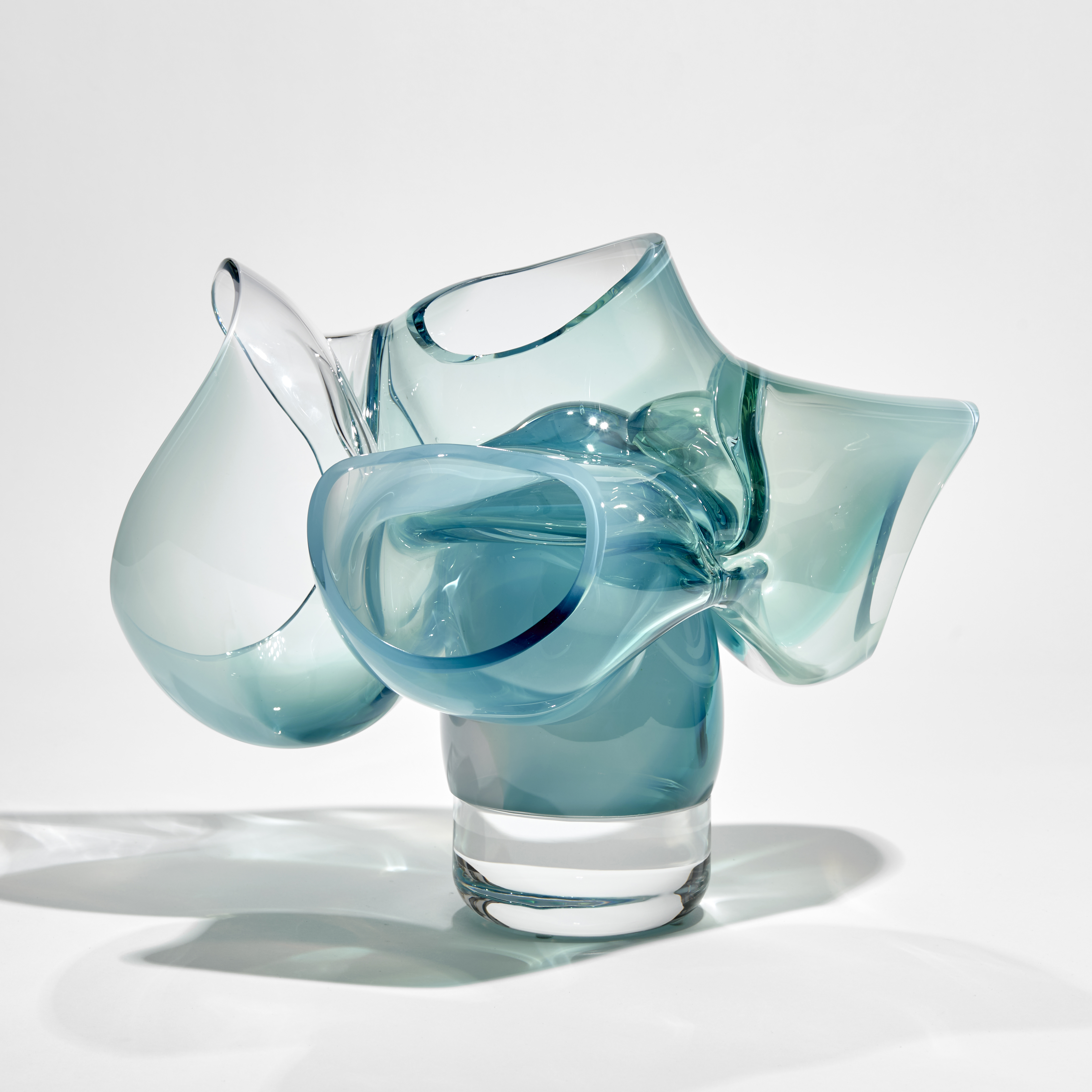 abstract sculpture of soft tubular bubbles in transparent clear and turquoise glass held aloft on a central solid trunk hand made from glass