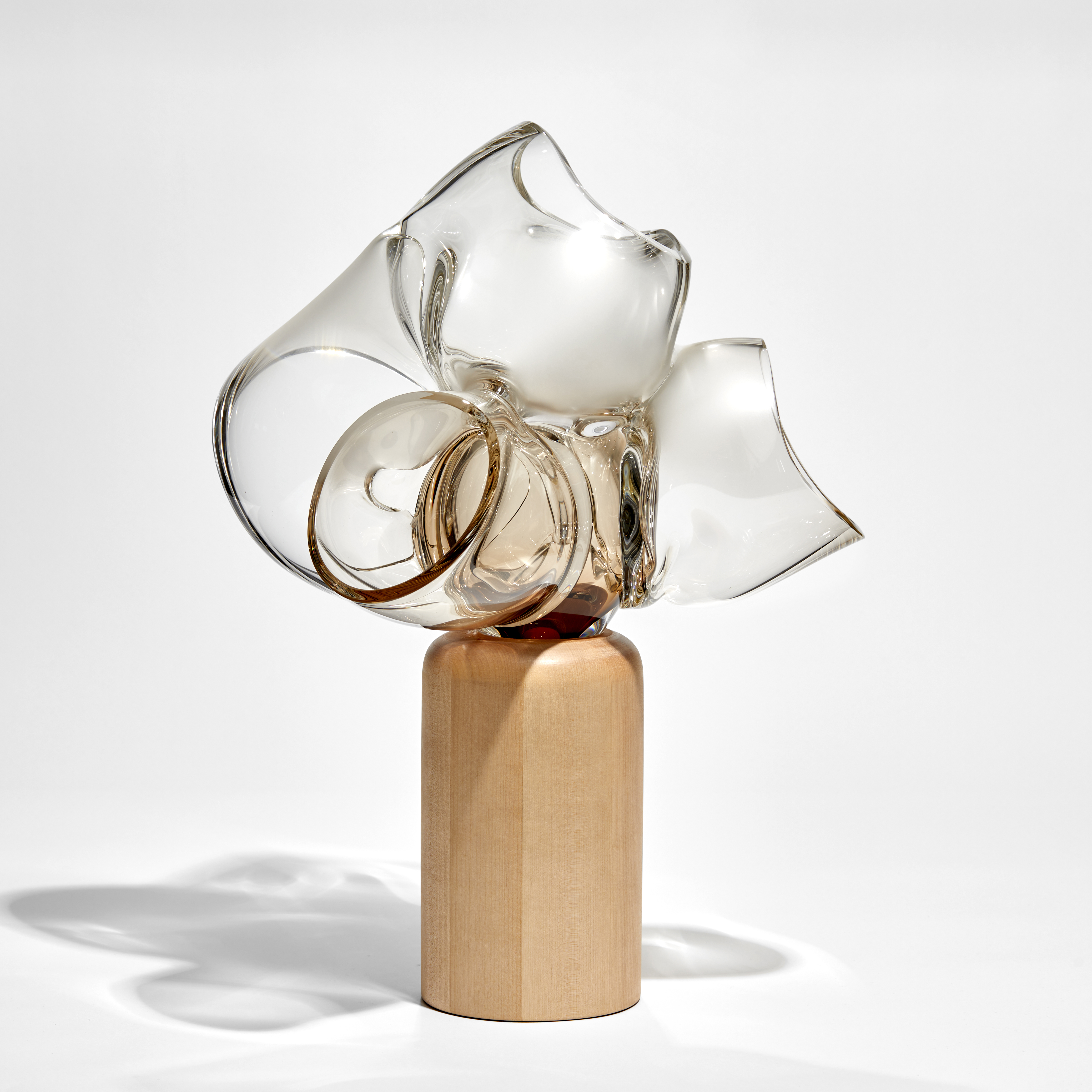 abstract human heart sculpture perched on a column of birch wood hand made from bronze tinted glass