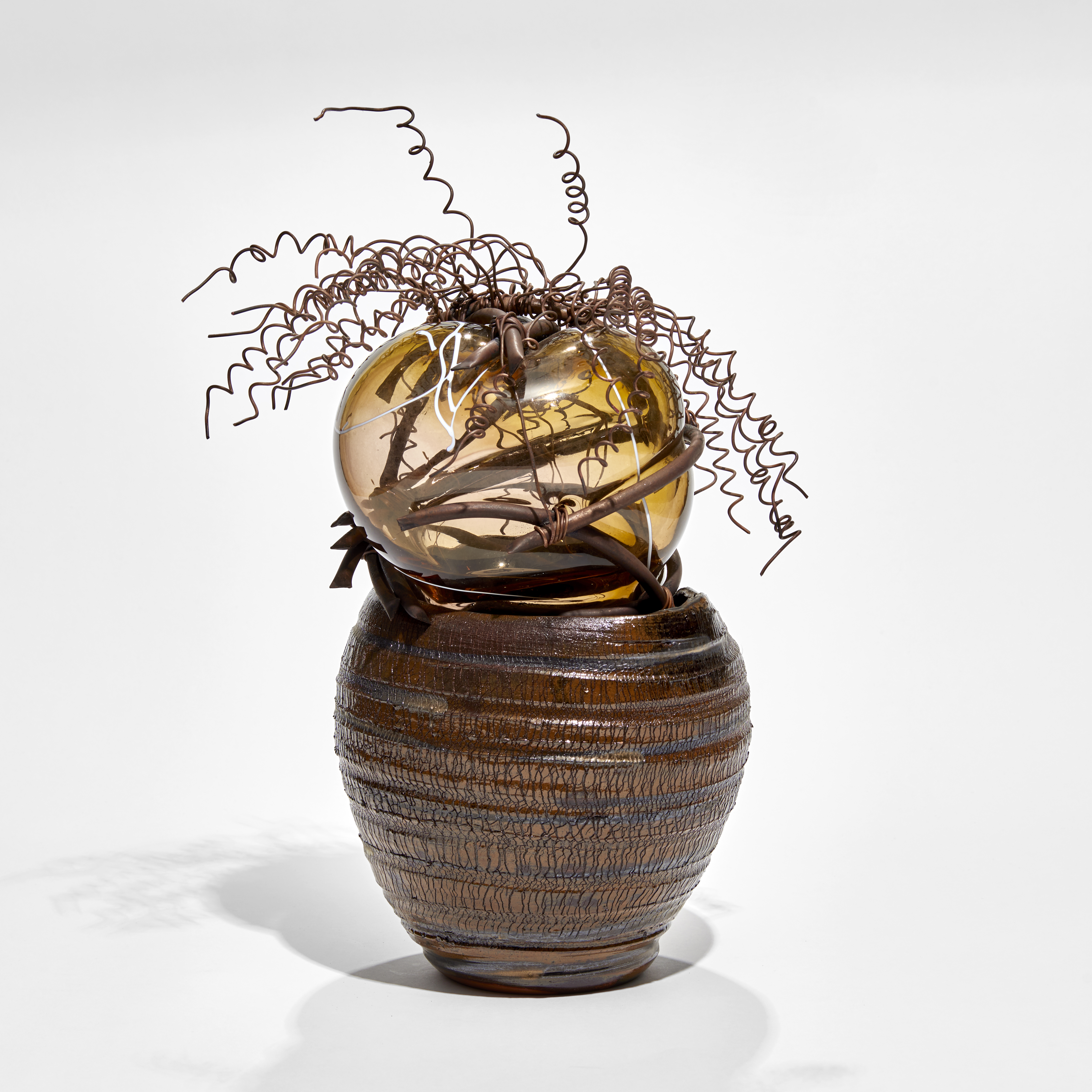 brown ridged ceramic urn containing a bursting forth bubble of amber glass bound in copper with copper wire cork screw hair