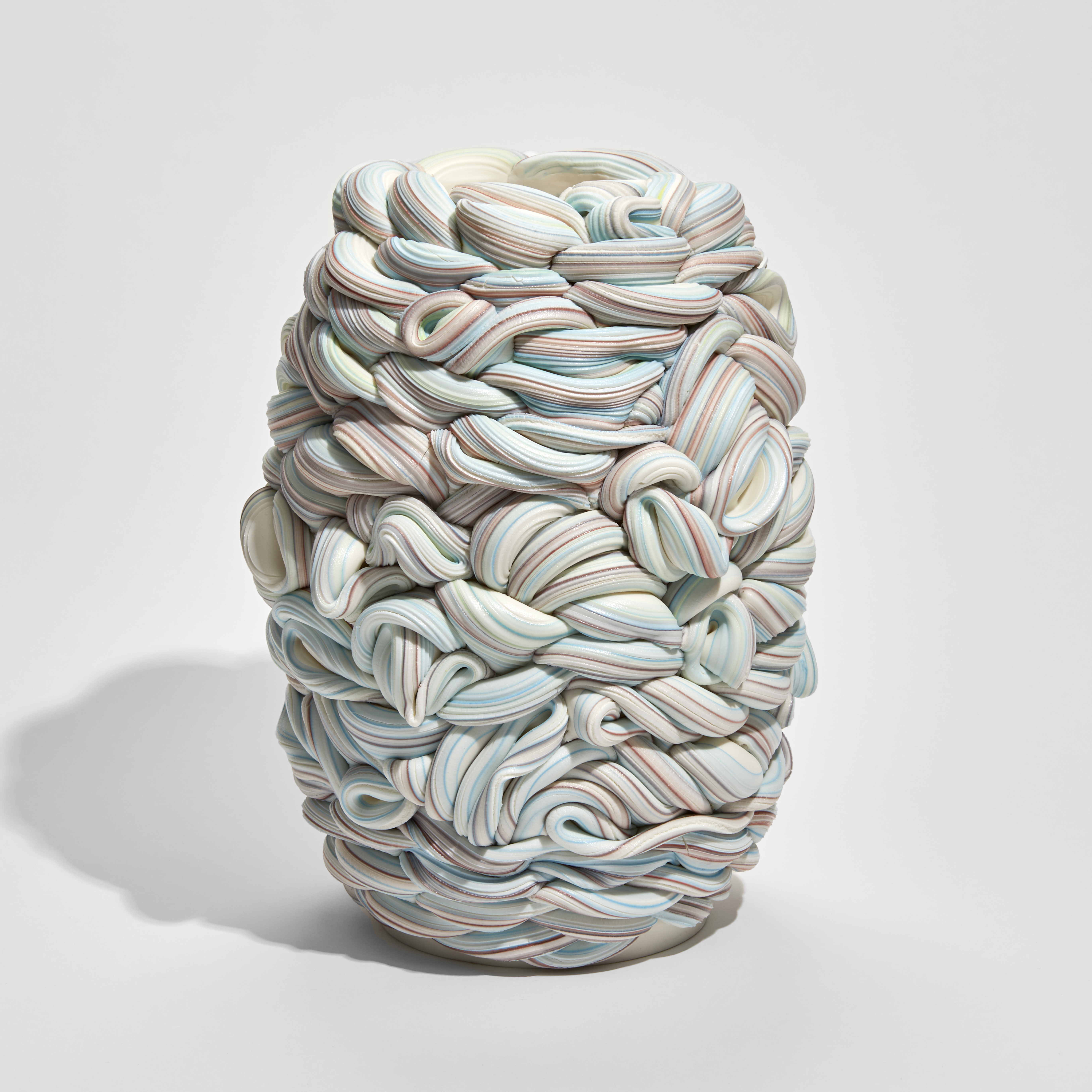 white blue and pink barrel shaped vessel that looks like a bobbin of wool hand made from parian porcelain