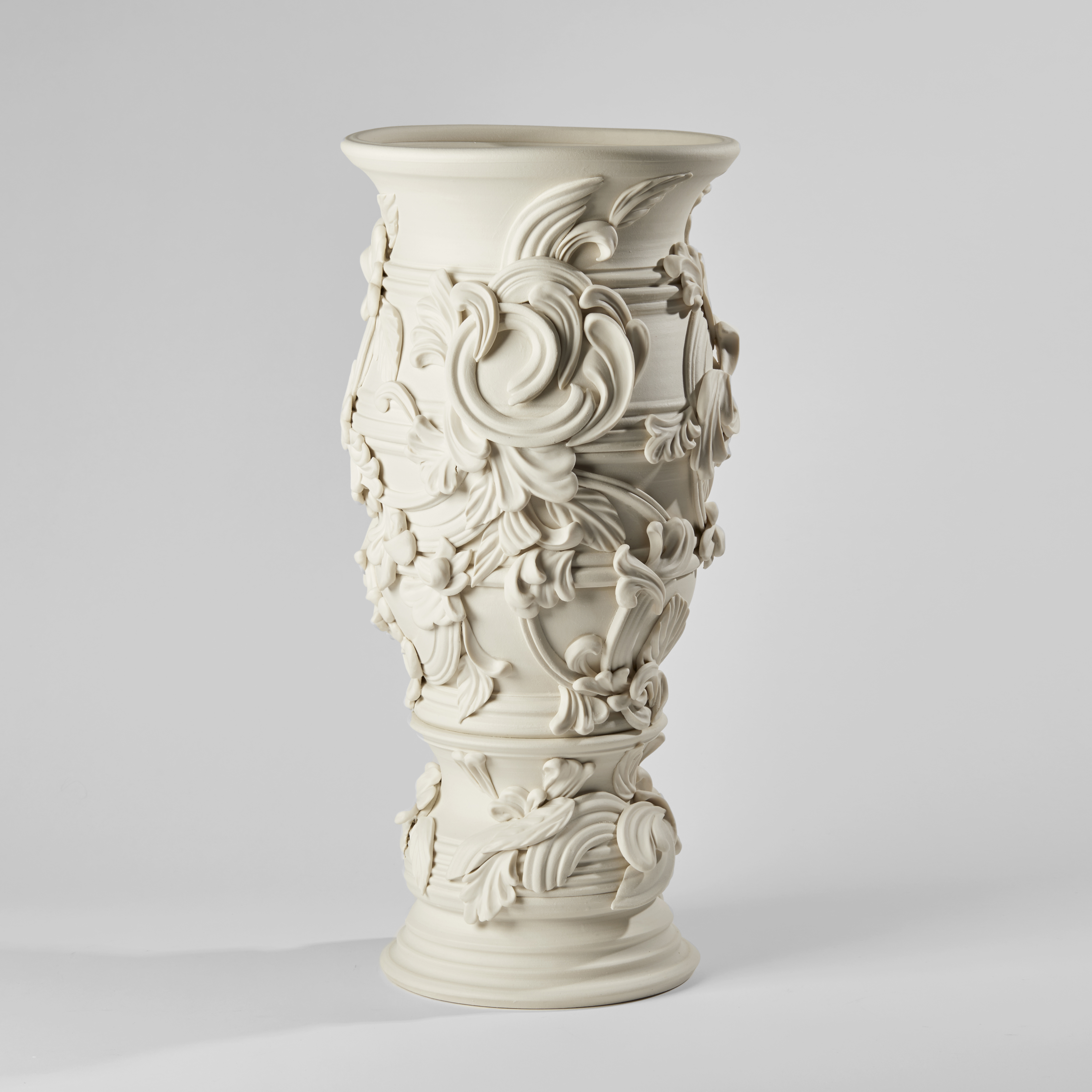 flared tall column shaped vase with banded ridges covered in organic swirls and floral motifs handmade from porcelain