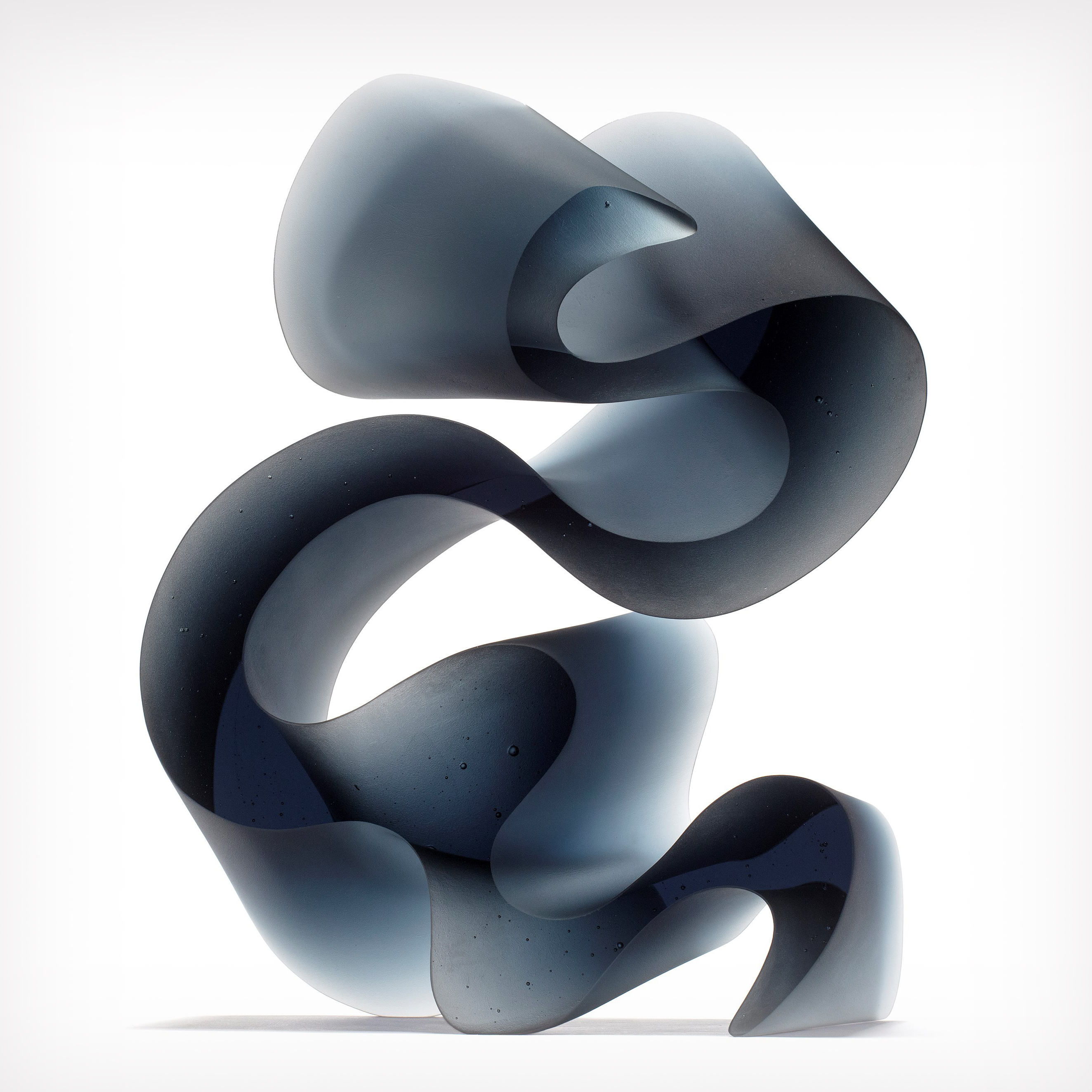 dark grey blue curved abstract ribbon lined sculpture hand made from cast glass standing on end