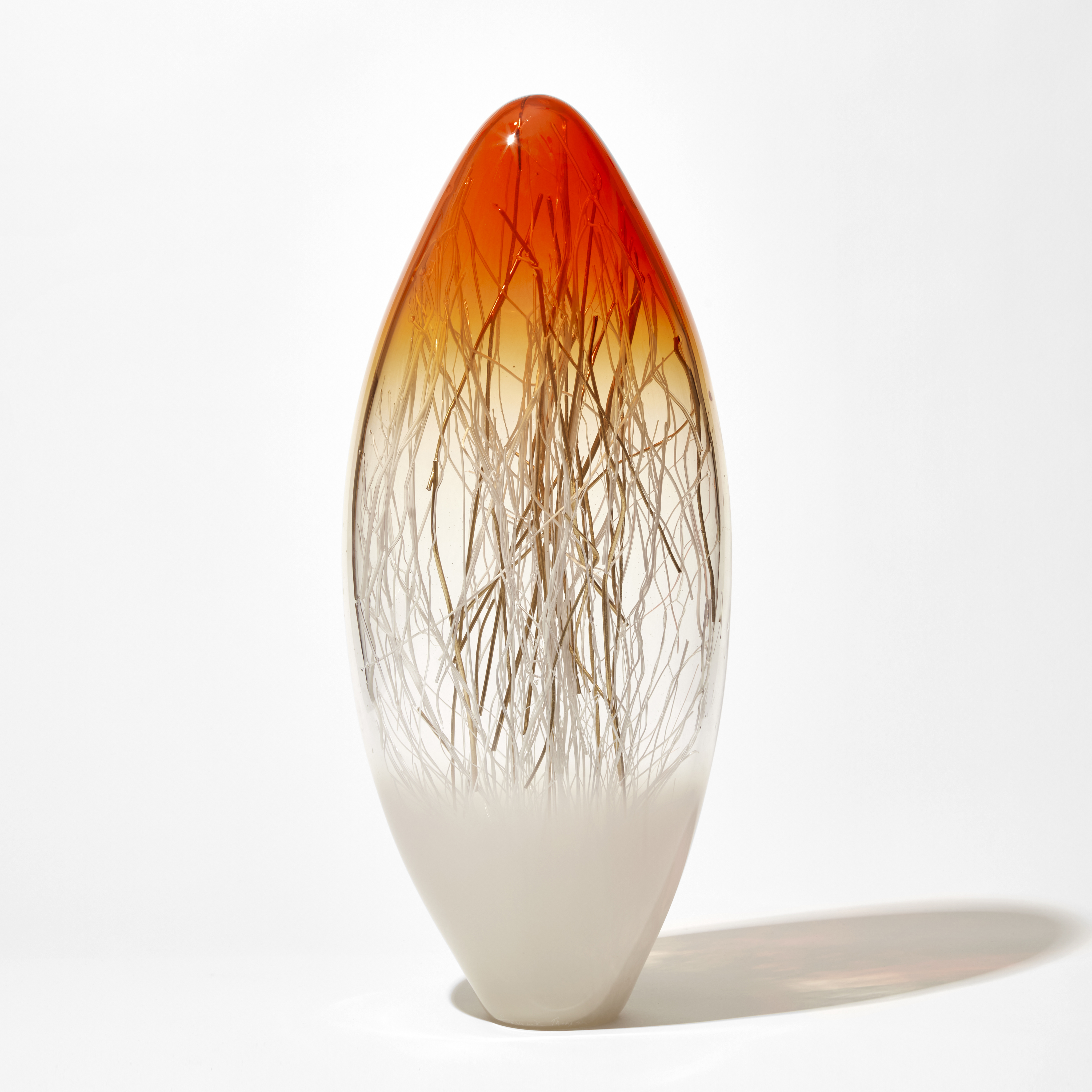 tall long ovoid sculpture with pointed top in bright orange fading to clear then white with interior filled with thin canes in white and gold hand made from glass