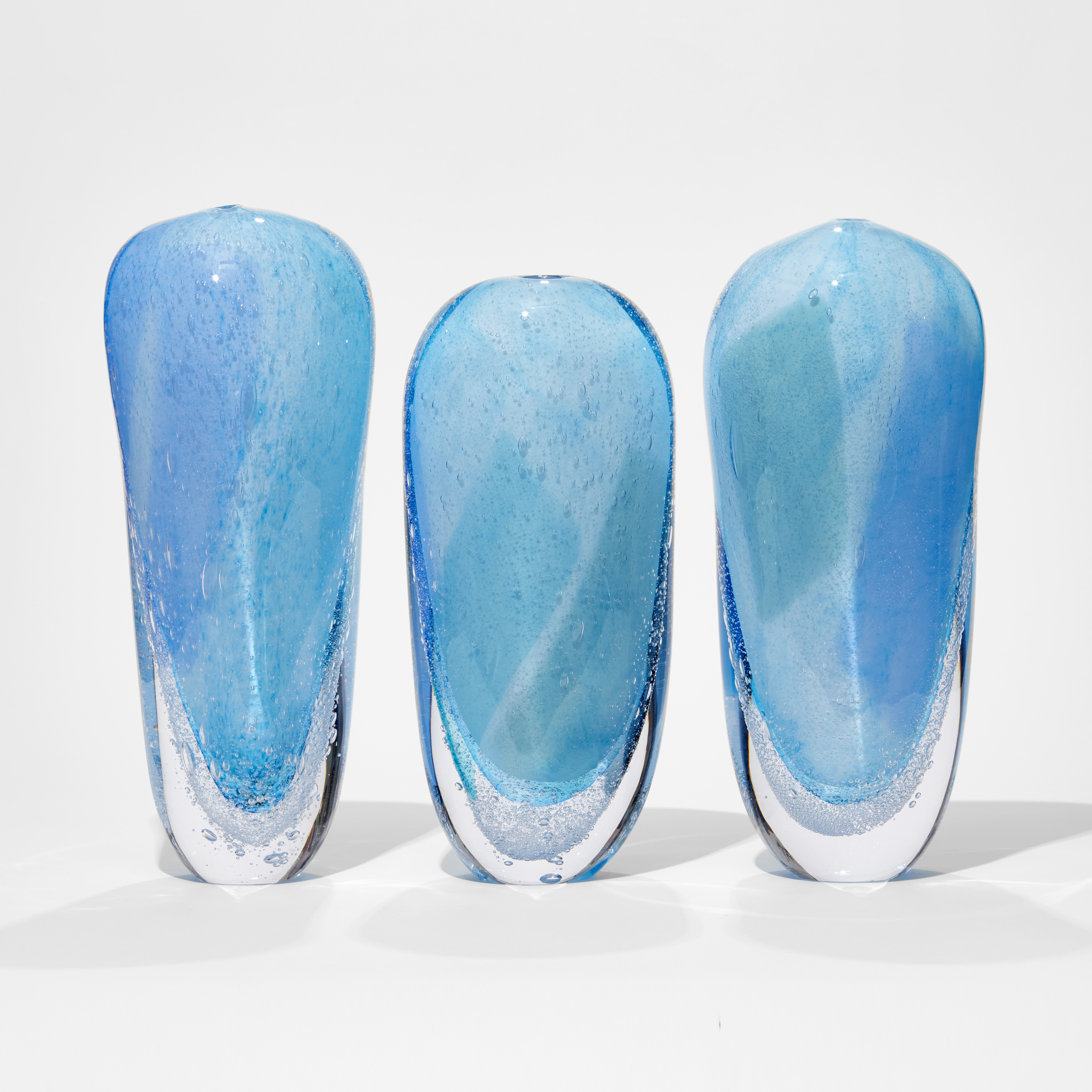 aqua light blue and clear tall soft forms based on icebergs with clear bottom lined with bubbles hand made from glass