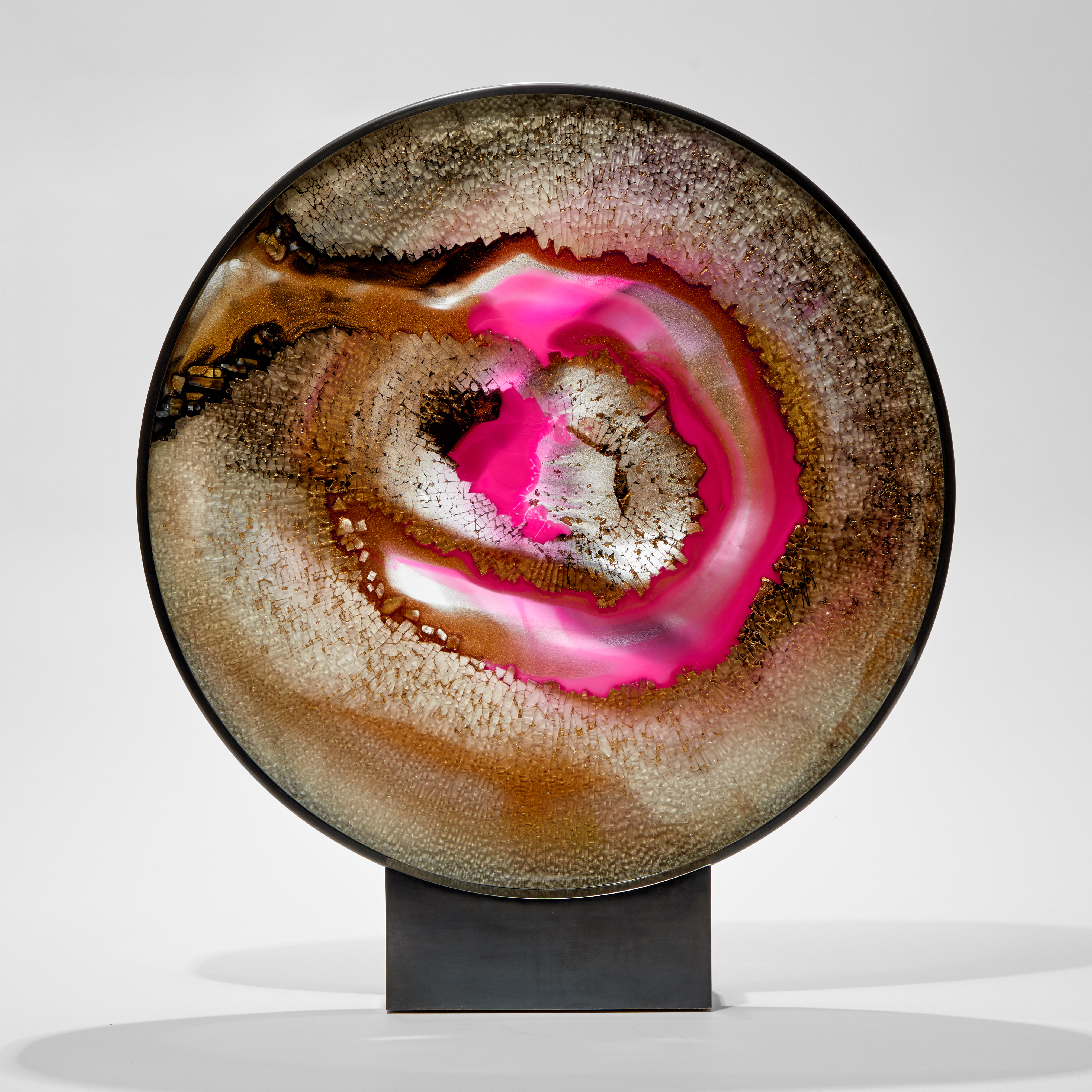 rounded 2d sculpture in metal frame and base made from shattered glass with trapped colours in gold black and bridge pink hand made