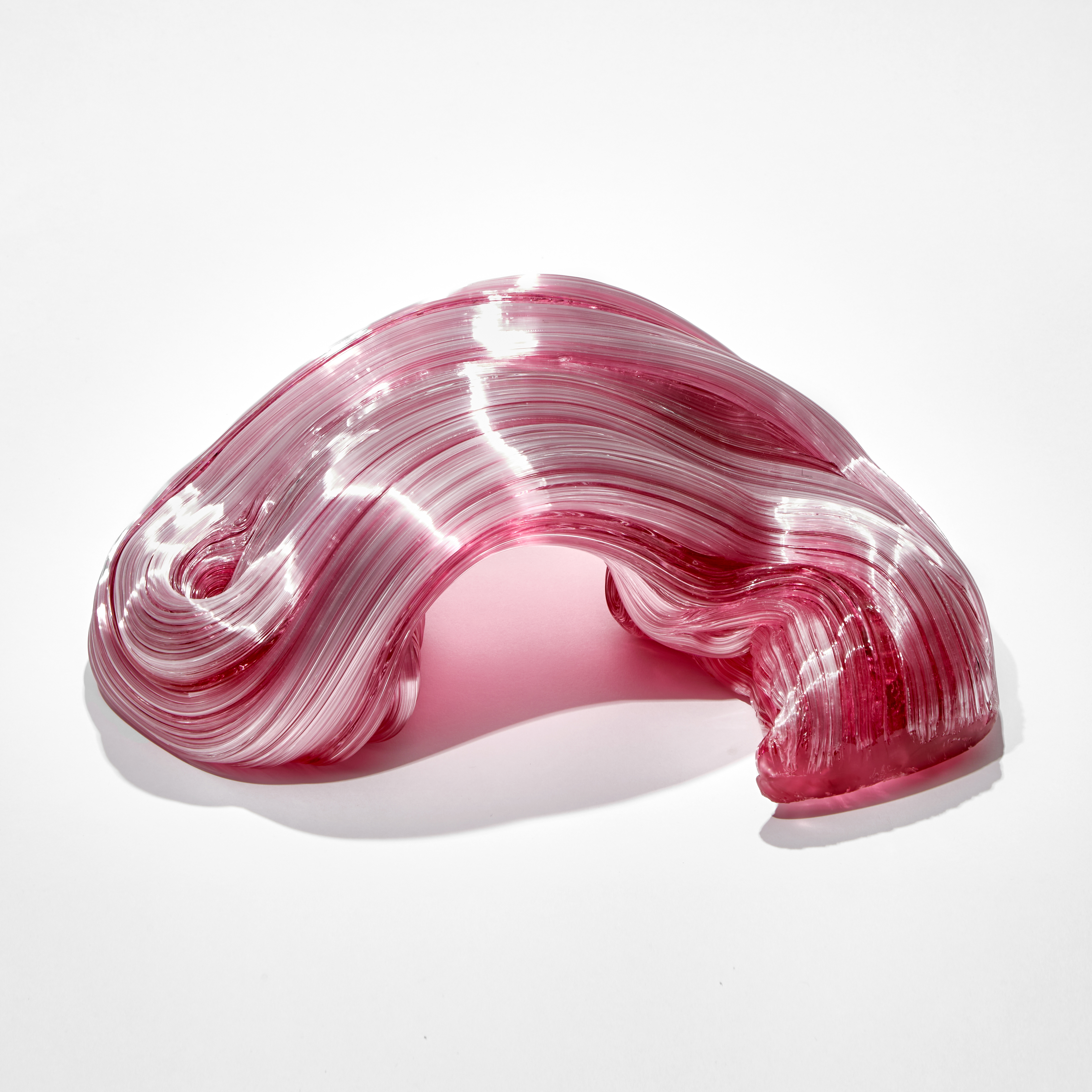 pink arched and bending ridged candy cane sculpture hand made from glass