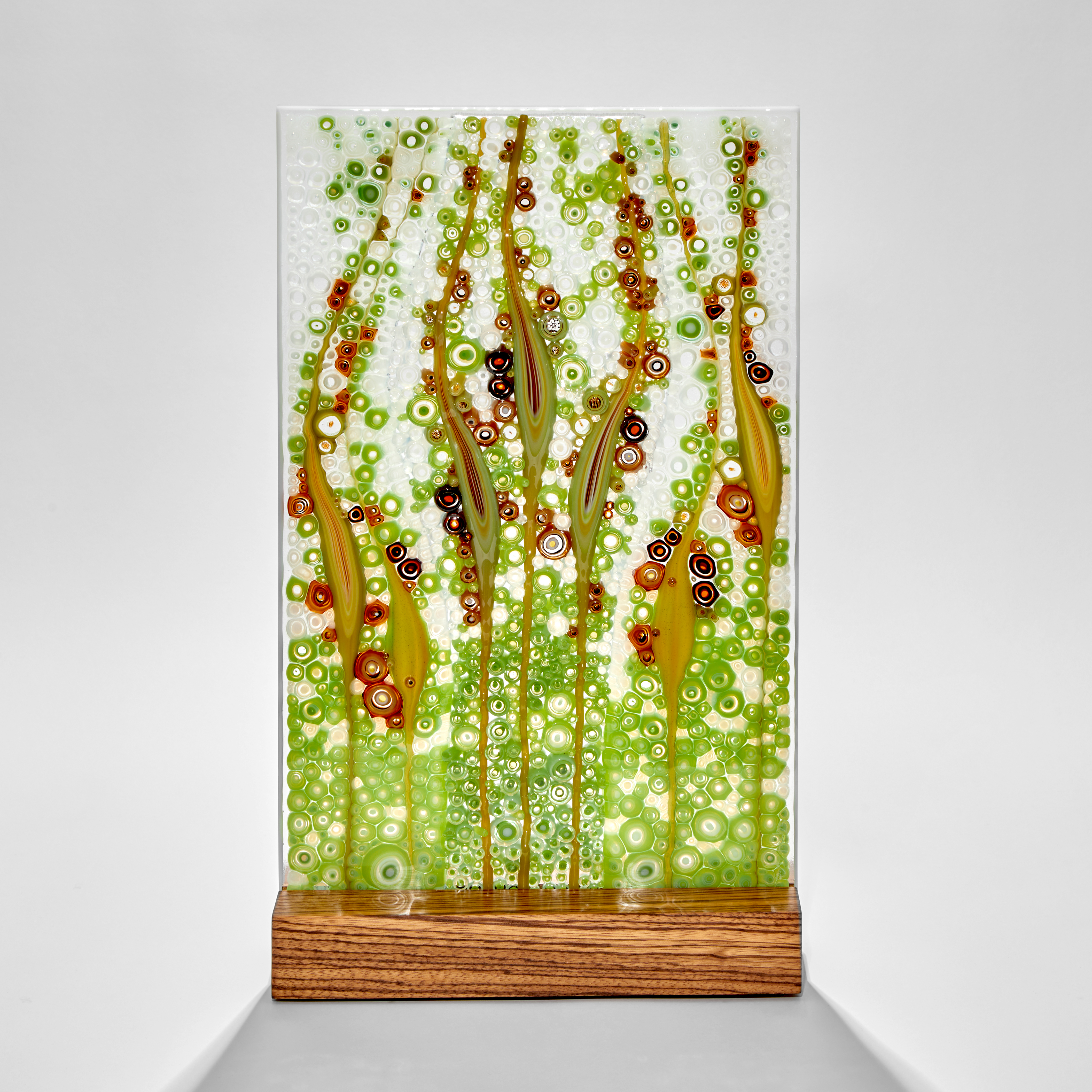 rectangular panel with bubbles and grass seed shapes in aqua blue green and deep red hand made from glass with a zebrano wood base