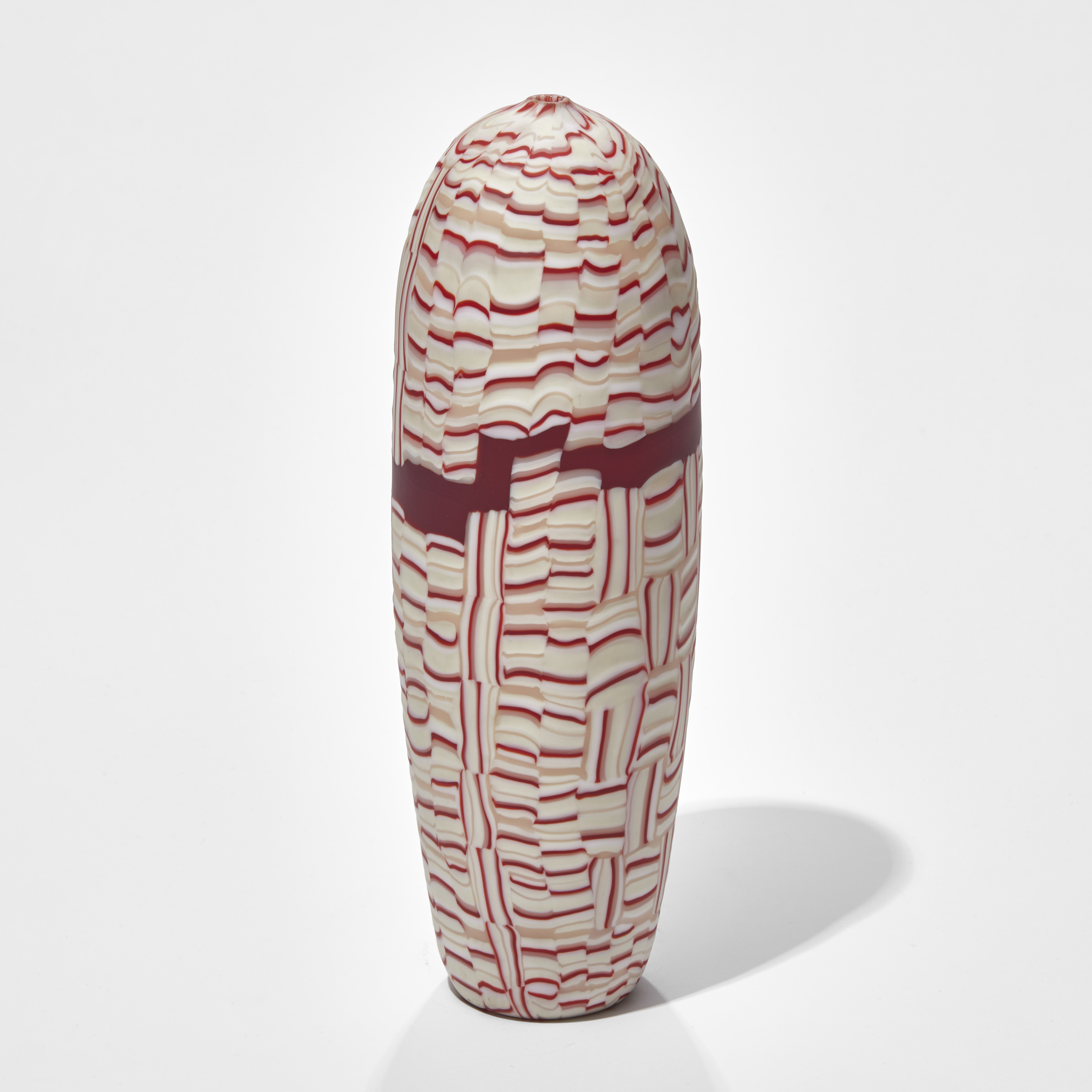 upright torpedo shaped vessel with abstract mosaic pattern in red white and pink hand made from glass