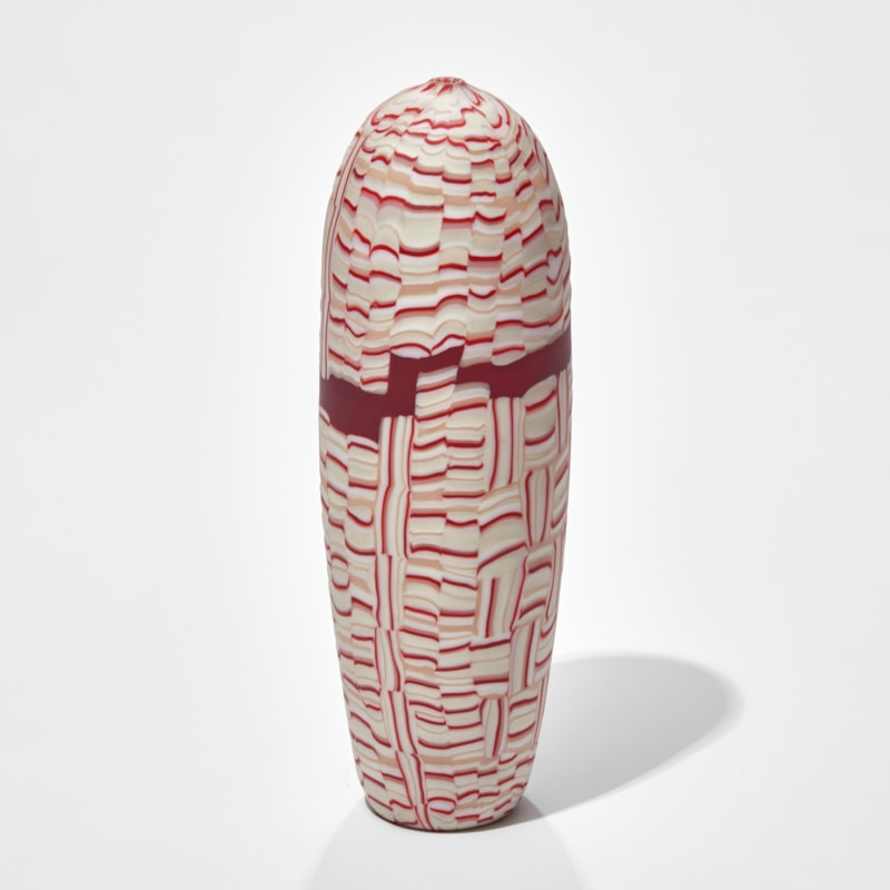upright torpedo shaped vessel with abstract mosaic pattern in red white and pink hand made from glass