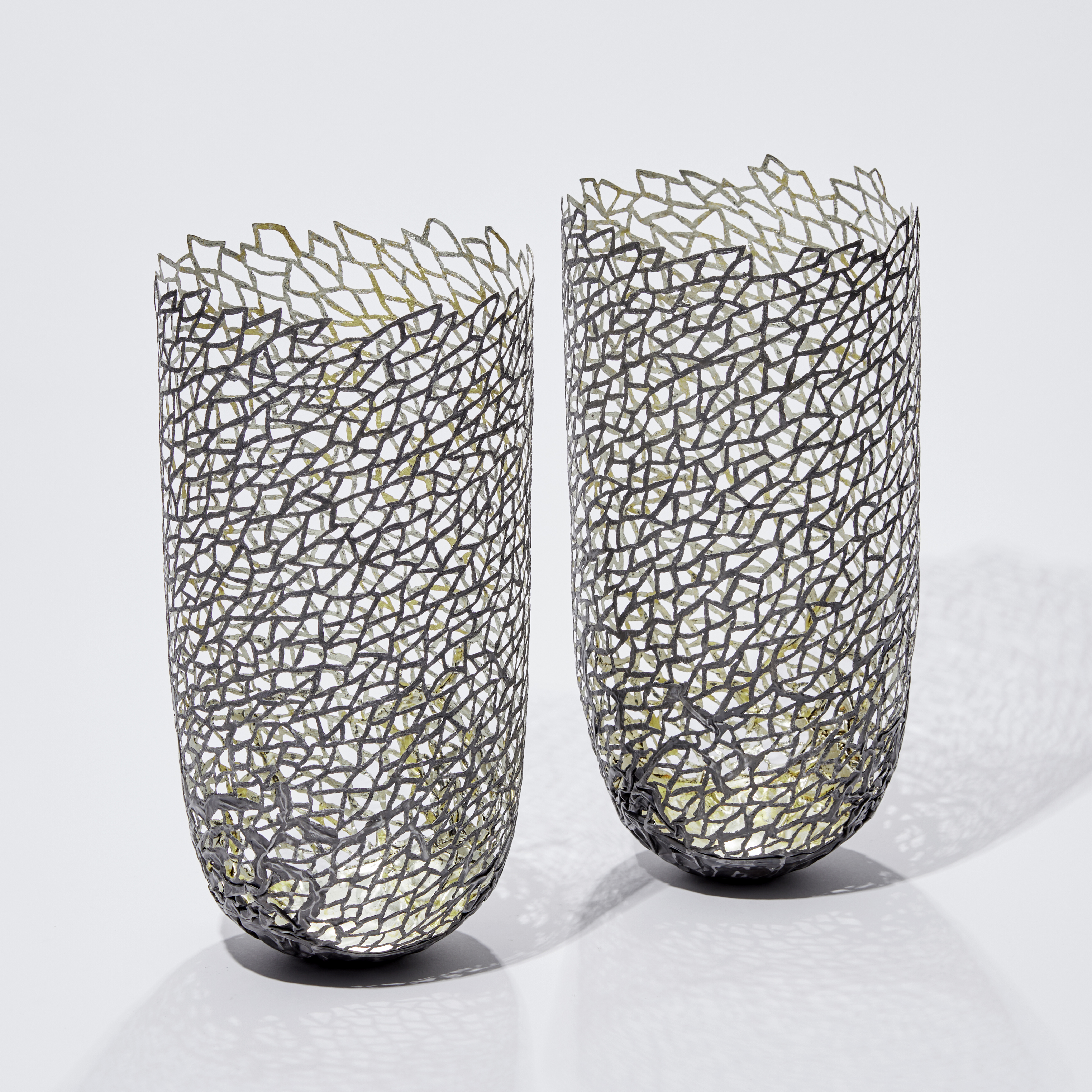 two modern art sculpted vessels made from steel and gold 