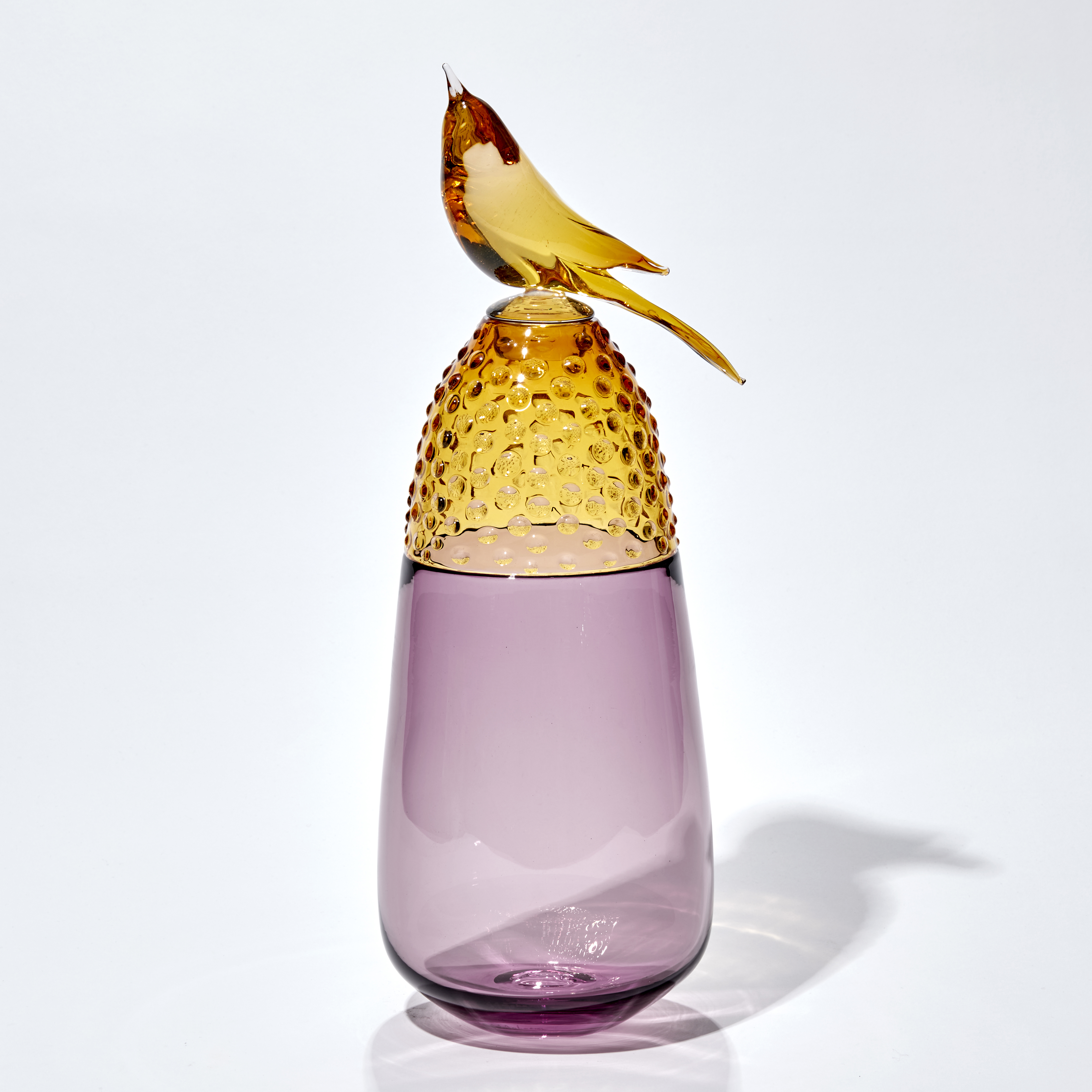 soft plum purple and golden amber vase with top third covered in raised dots with a stopper adorned with a golden amber bird hand made from glass