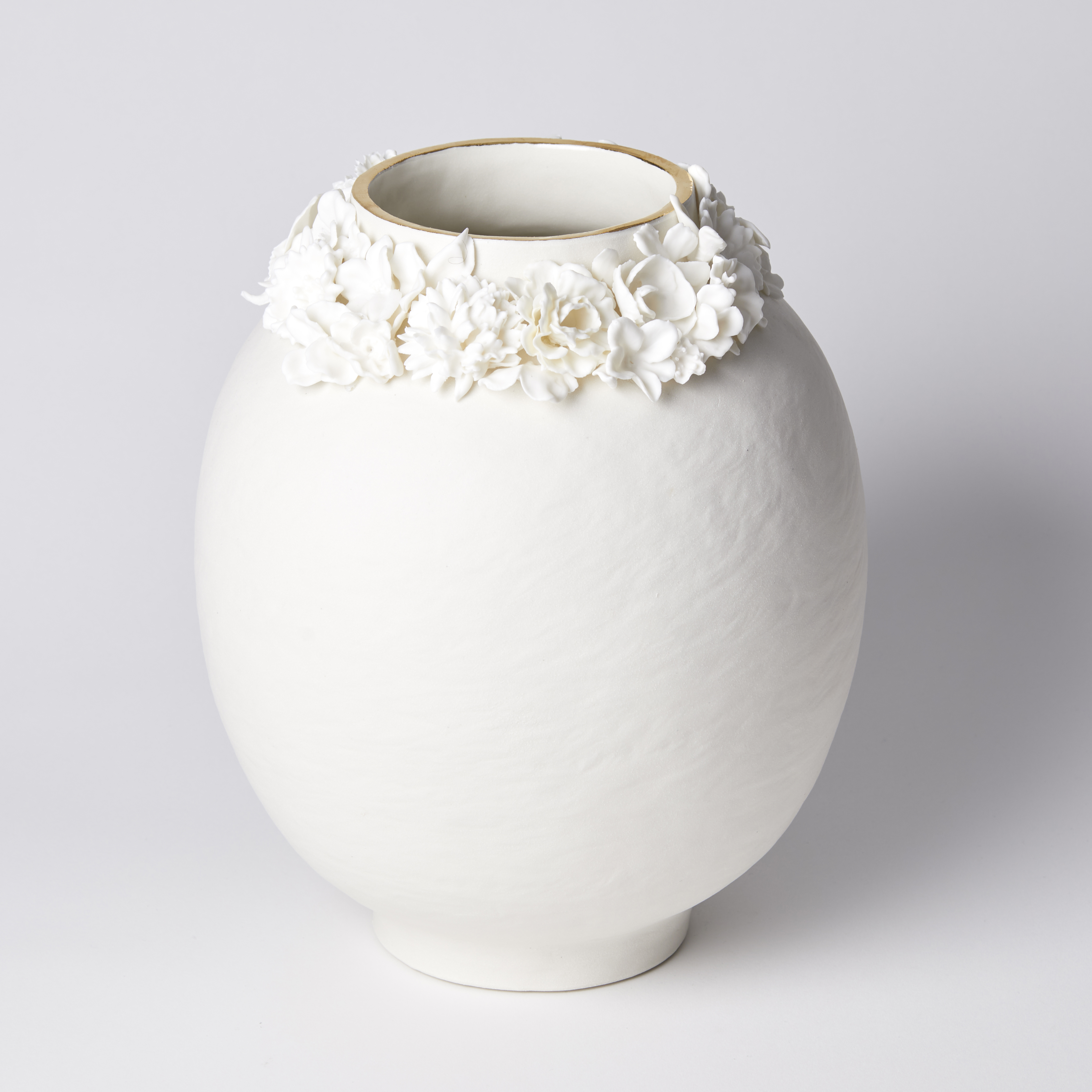 off white rounded vase with uneven surface and floral adornment around the opening with final band on gold on the rim handmade from porcelain