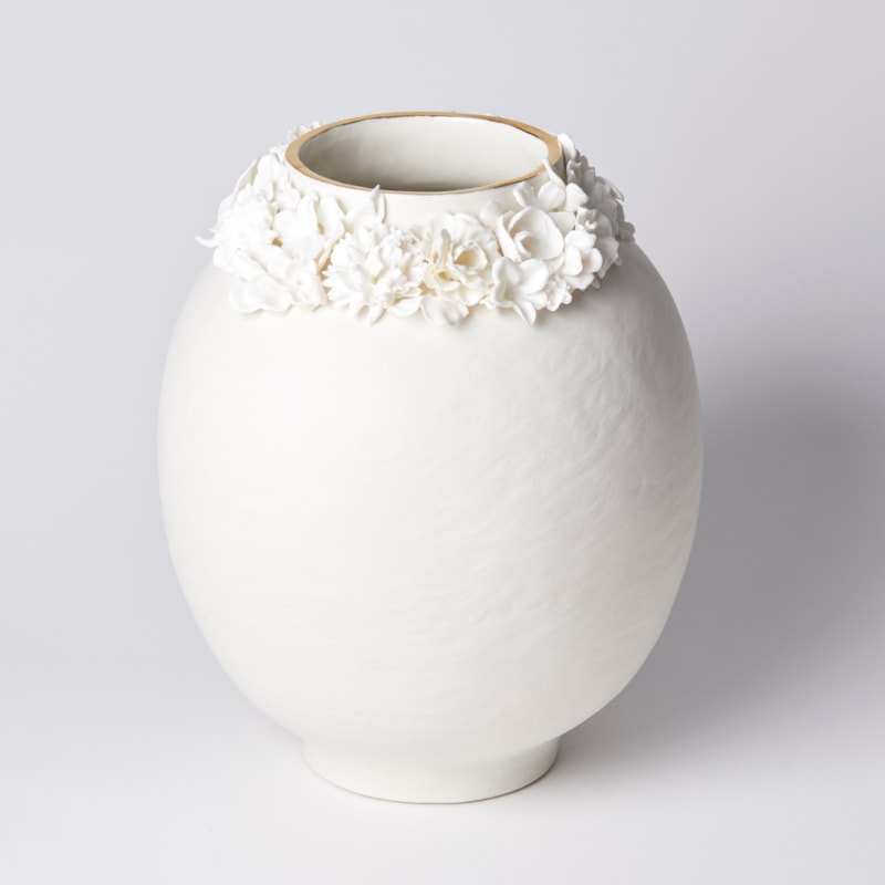off white rounded vase with uneven surface and floral adornment around the opening with final band on gold on the rim handmade from porcelain