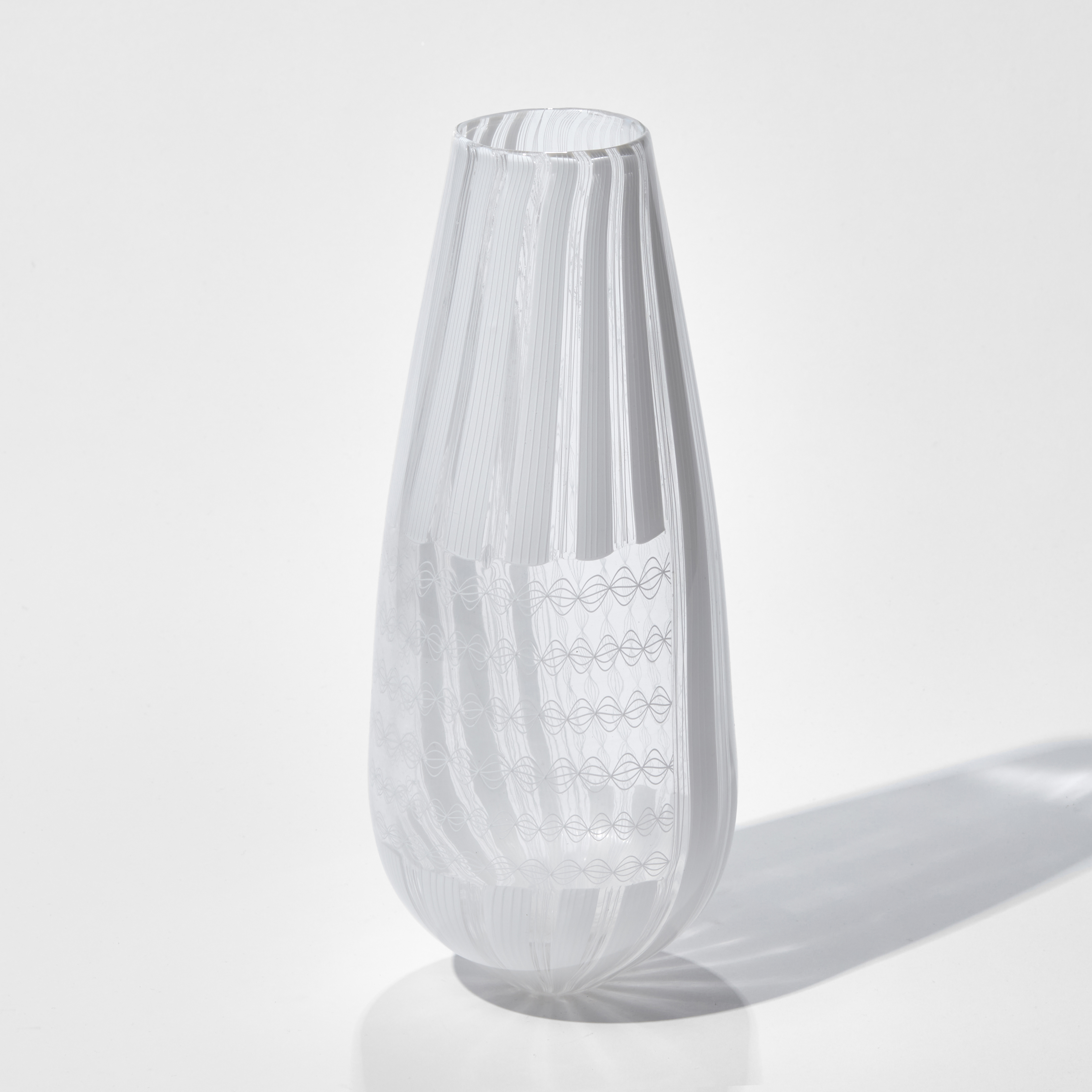 white and clear teardrop shaped vase with straight cut off top covered in intricate non symmetrical white patterns hand made from glass