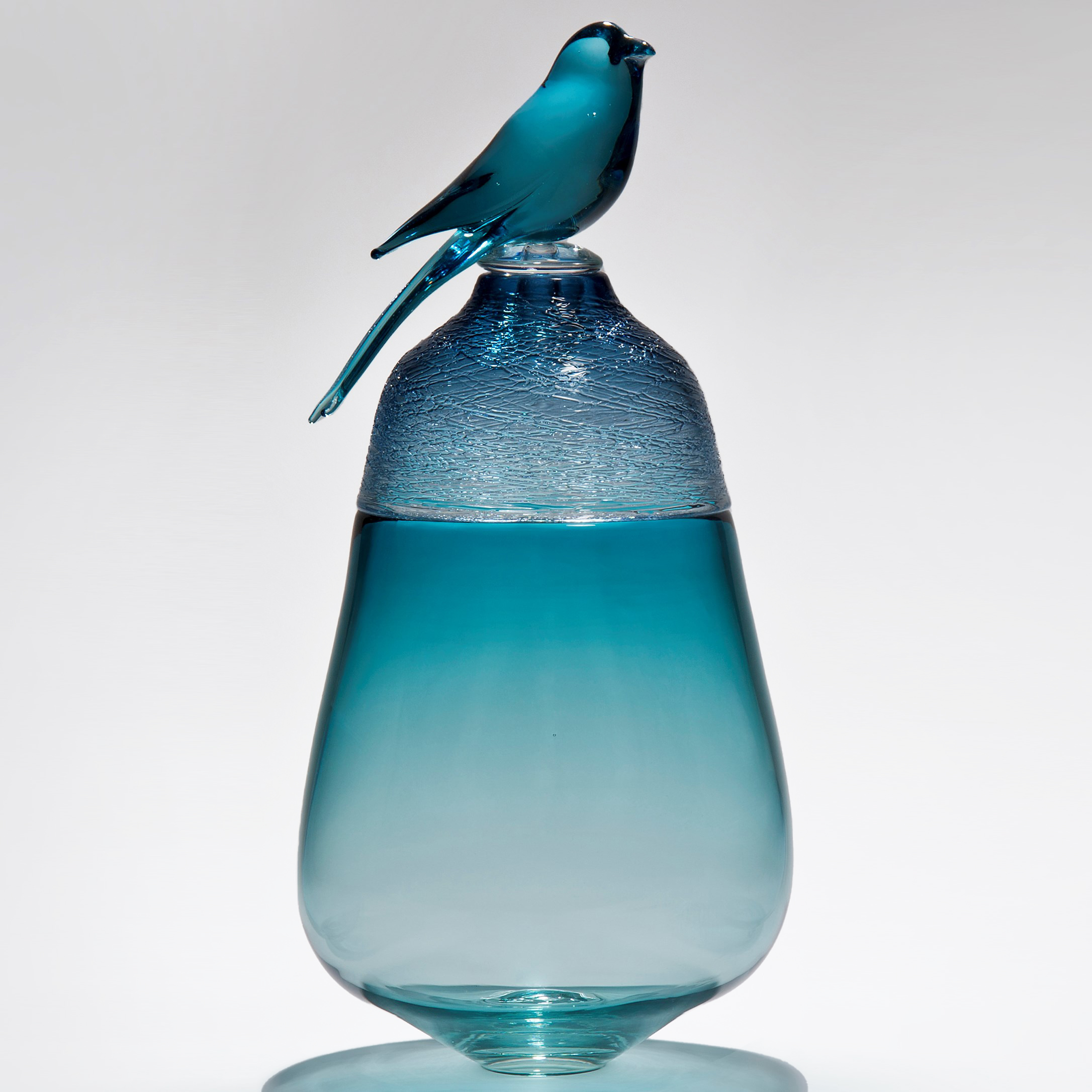light blue coloured glass artwork of bird sat on top of vessel