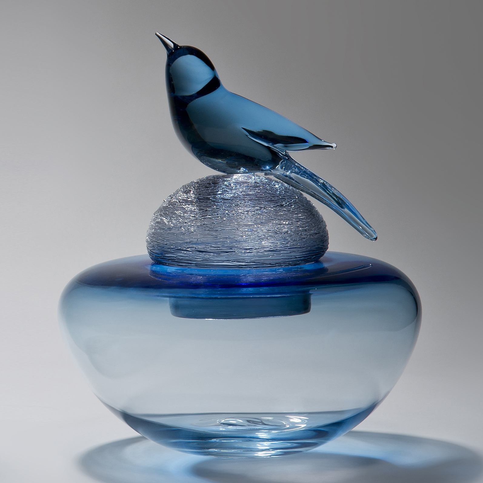blue glass sculpture of funeral urn with bird on top