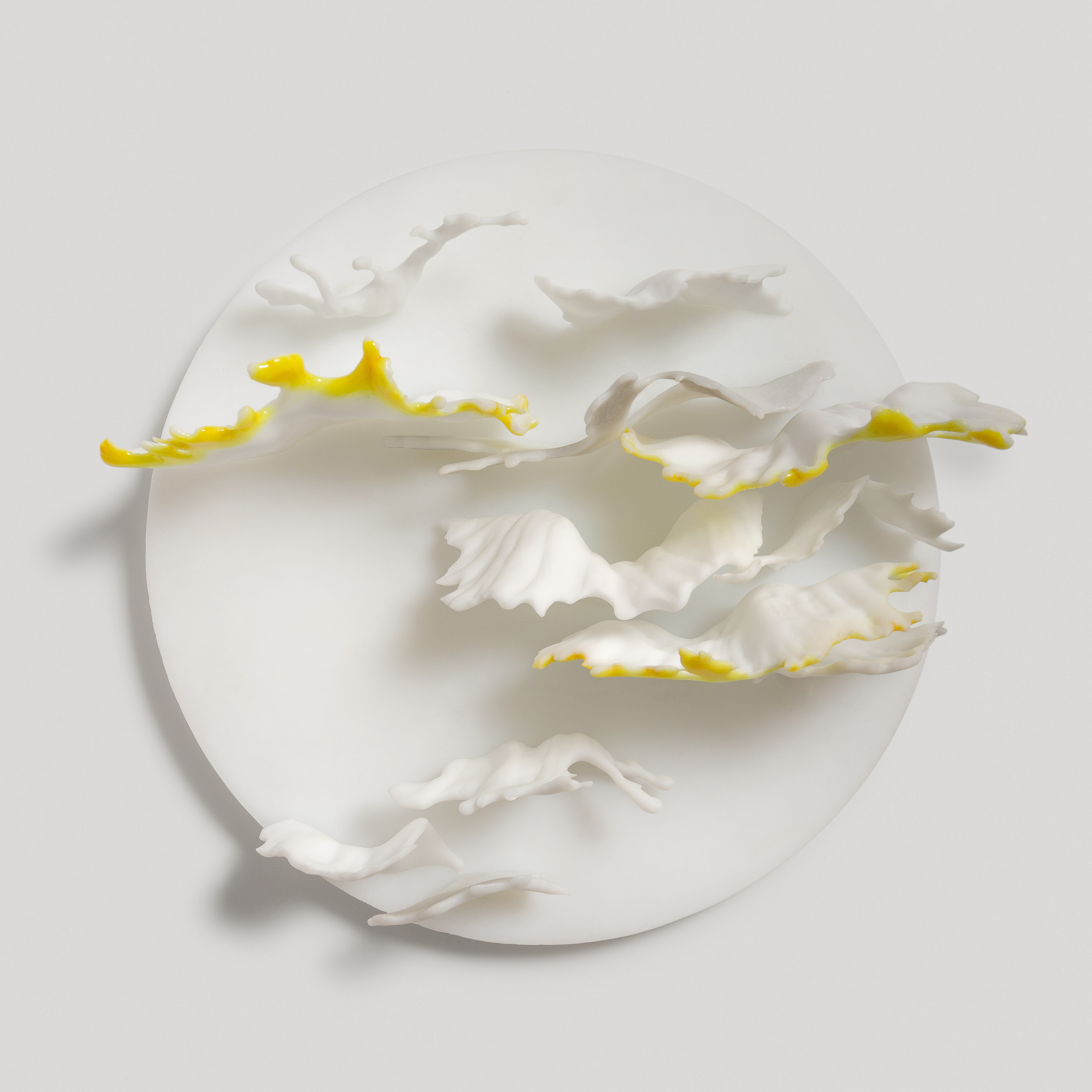 round white wall mounted disc with reaching out organic fronds in white grey and amber yellow hand made from glass