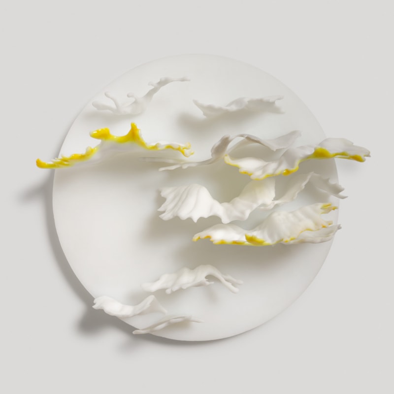 round white wall mounted disc with reaching out organic fronds in white grey and amber yellow hand made from glass