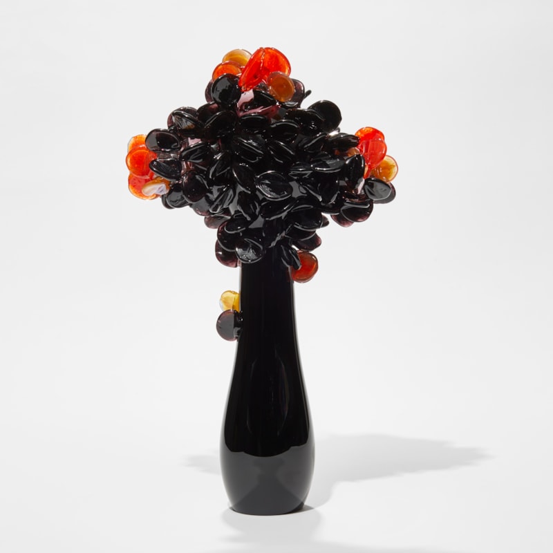 tall shiny black sleek simplified tree sculpture with top covered in clustered round lollipop leaves in black orange and amber hand made from glass