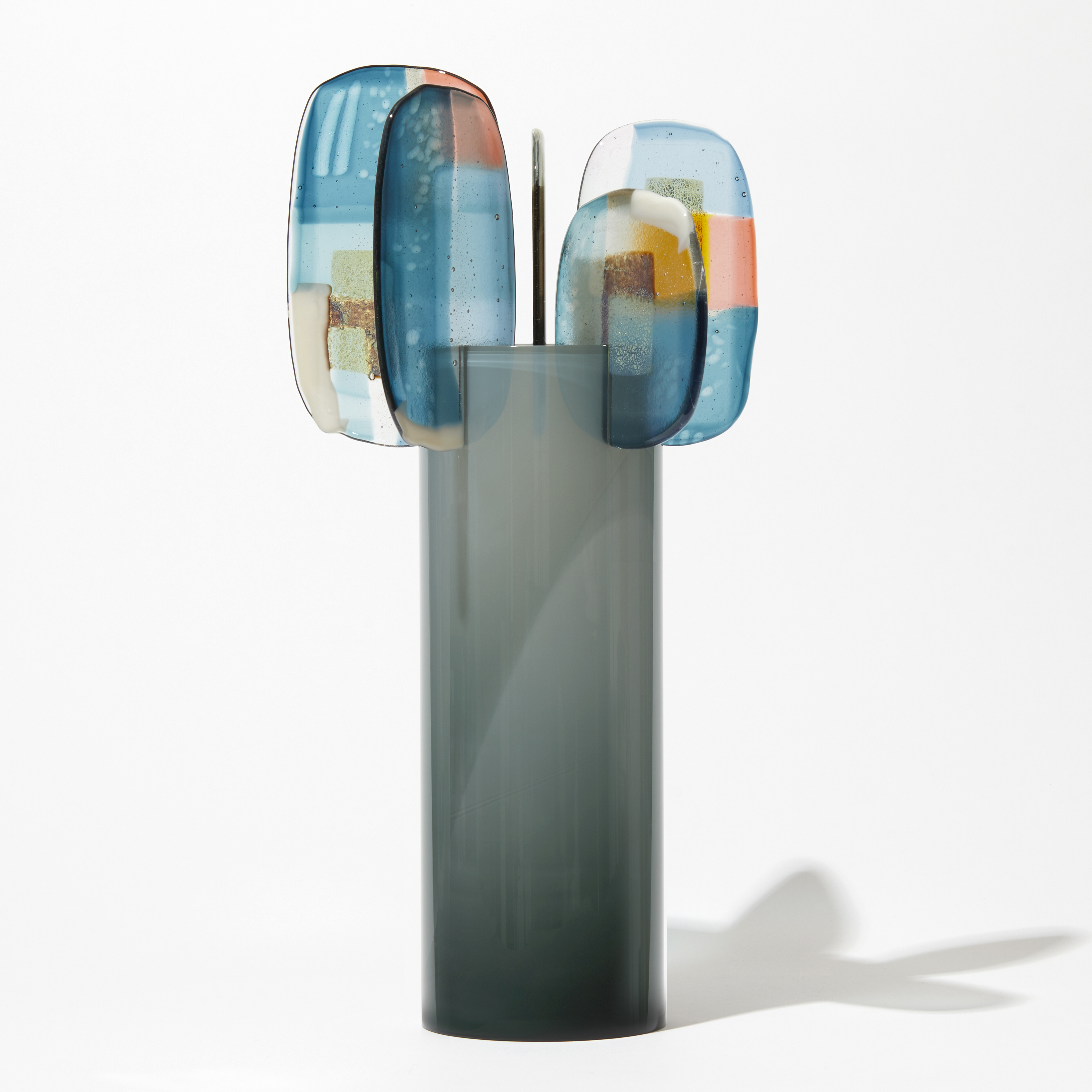 shiny fading from dark to light grey at the top cylinder with rounded leaves at the top with abstract patterns in teal blue pink opal white and gold hand made from glass