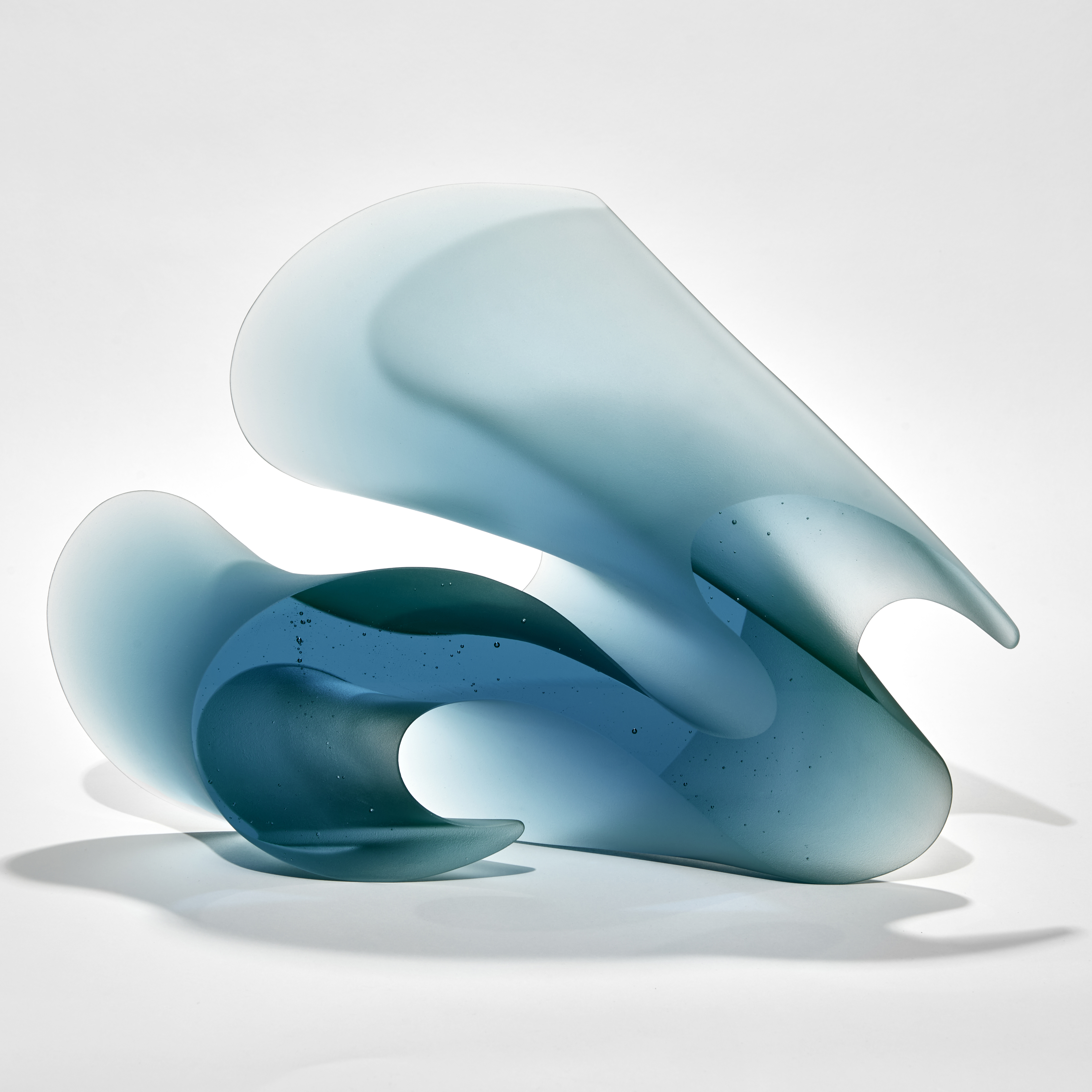 aqua blue curved standing abstract sculpture with two flat shiny parallel sides with the opposed sides curved and matt