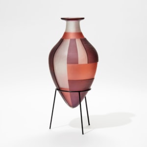 aubergine clear and pink bottle with wide top lip and pointed bottom with block bold pattern sat within in a black steel stand hand made from glass