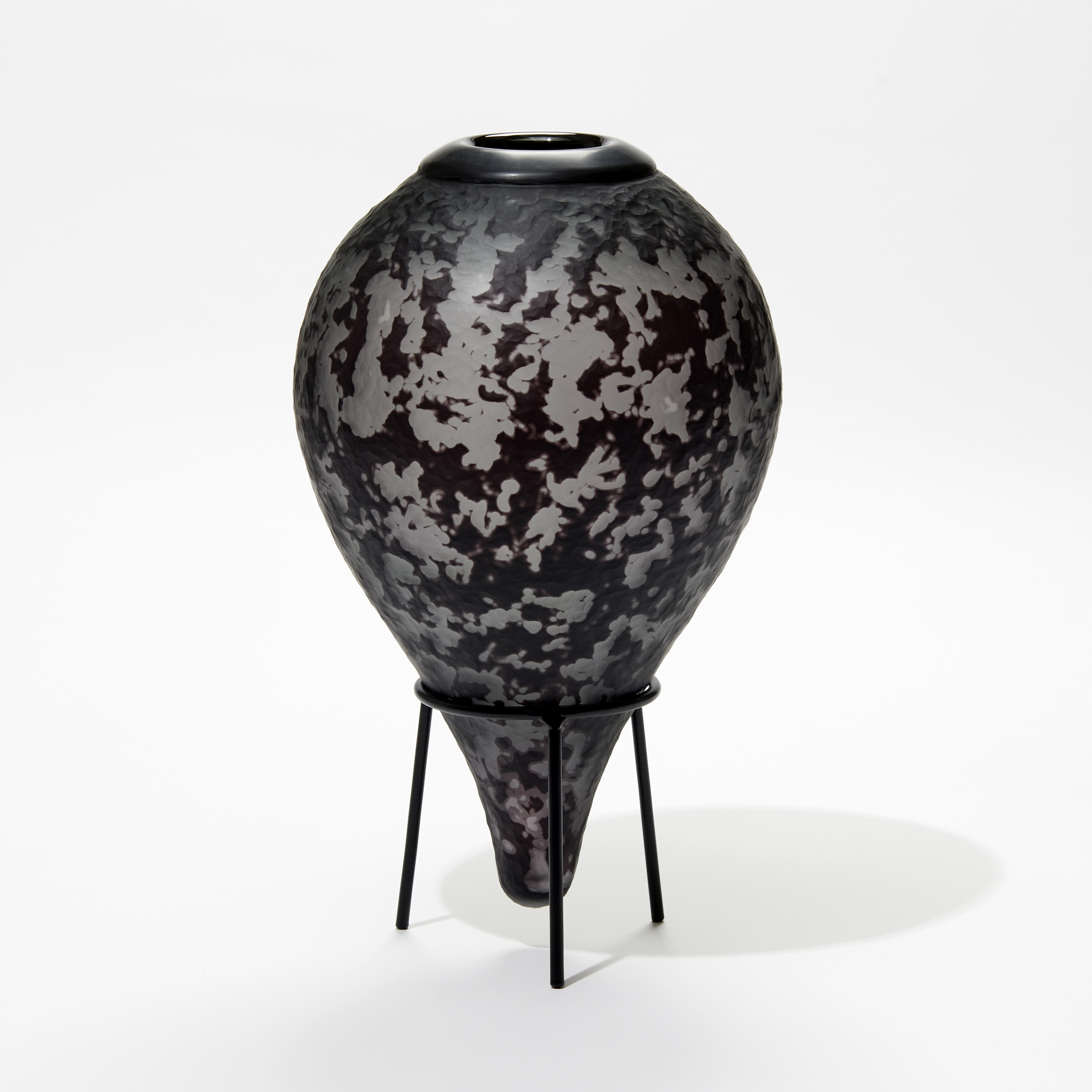 inverted teardrop bottle with organic texture in black and grey with black cuff on the top hand made from glass with black metal stand