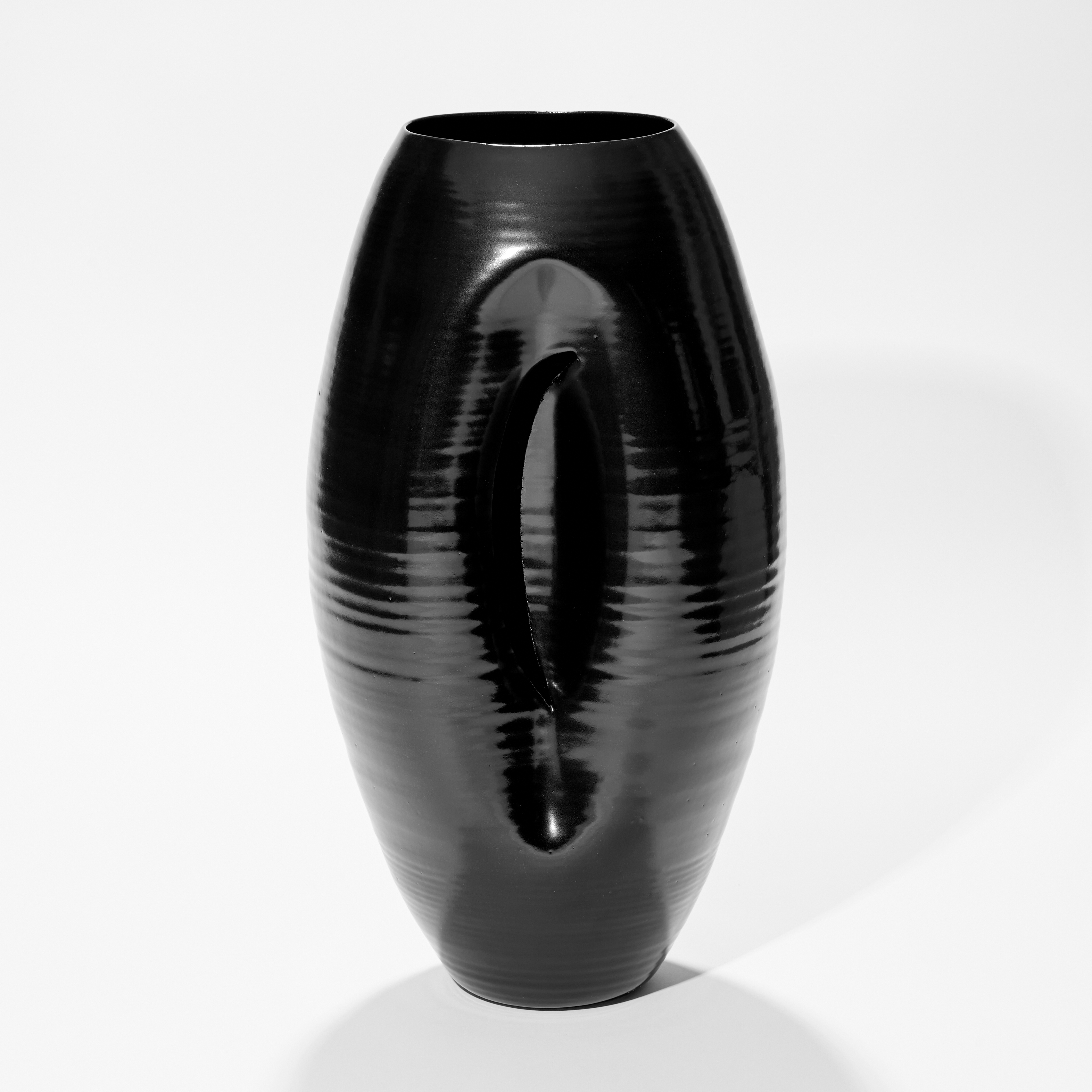 tall rounded oval shiny black vase with inverted front edge with inner curved cut revealing the interior hand made from ceramic