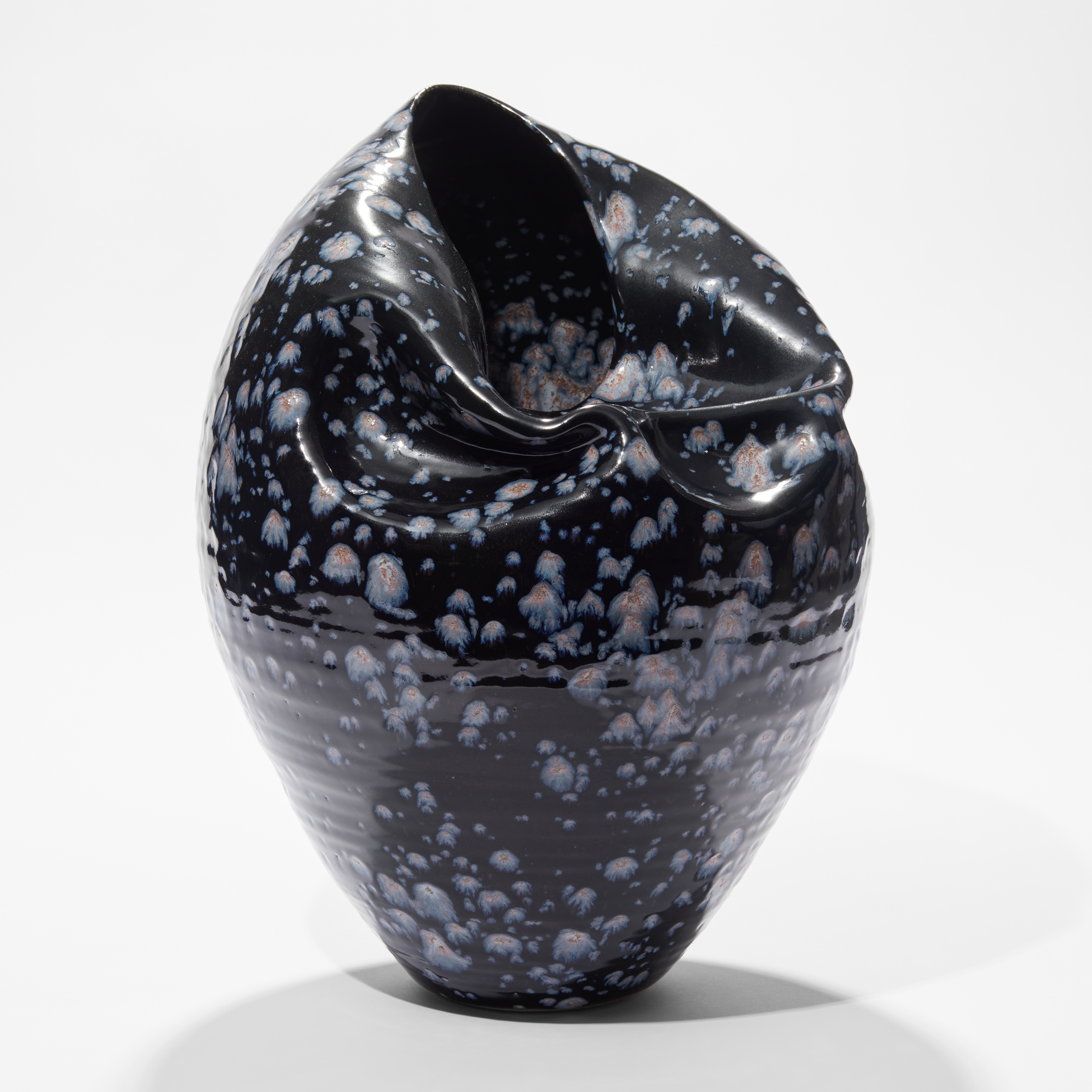 black blue with light blue splodges tapered based rounded vessel with wrinkled lightly collapsed side and opening hand made from ceramic