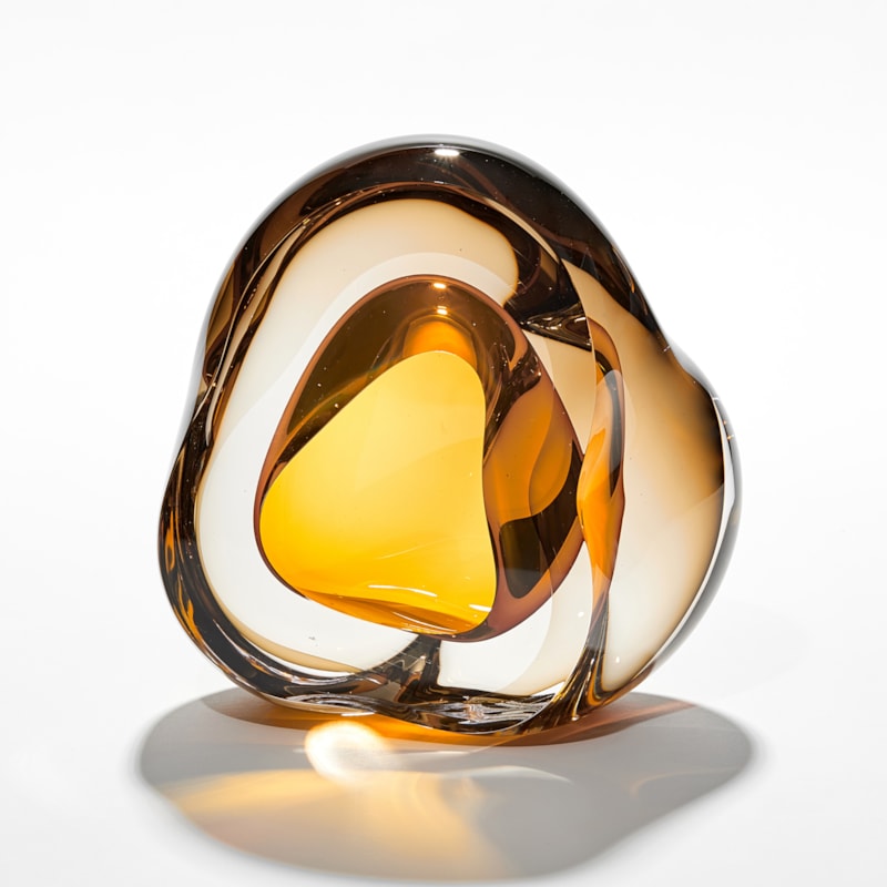 brilliant rich transparent amber amorphous sculpture with central middle organic hole in brilliant gold hand made from glass