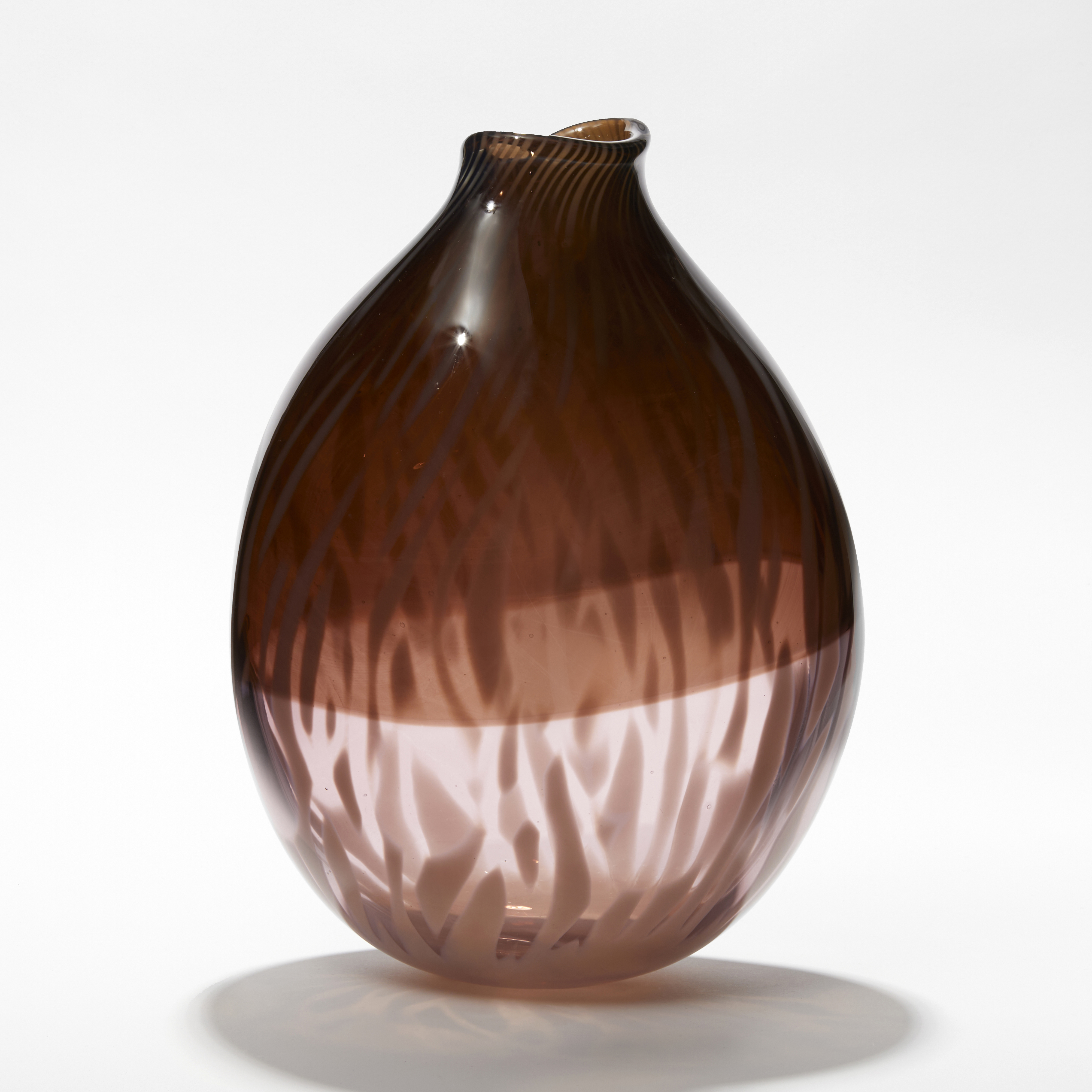rounded oval transparent vessel with bottom half in soft pink the top in sepia aubergine with an organic abstract feathered surface pattern hand made from glass