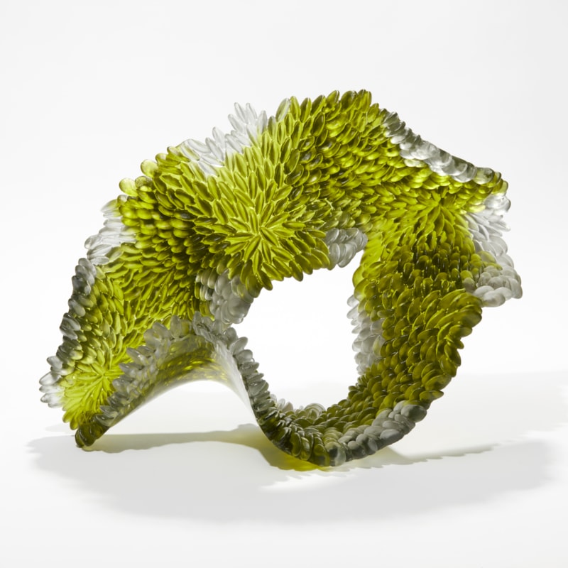organic standing sculpture in green grey and clear in the shape of a softened draped loop with textured one side the other polished hand made from cast glass