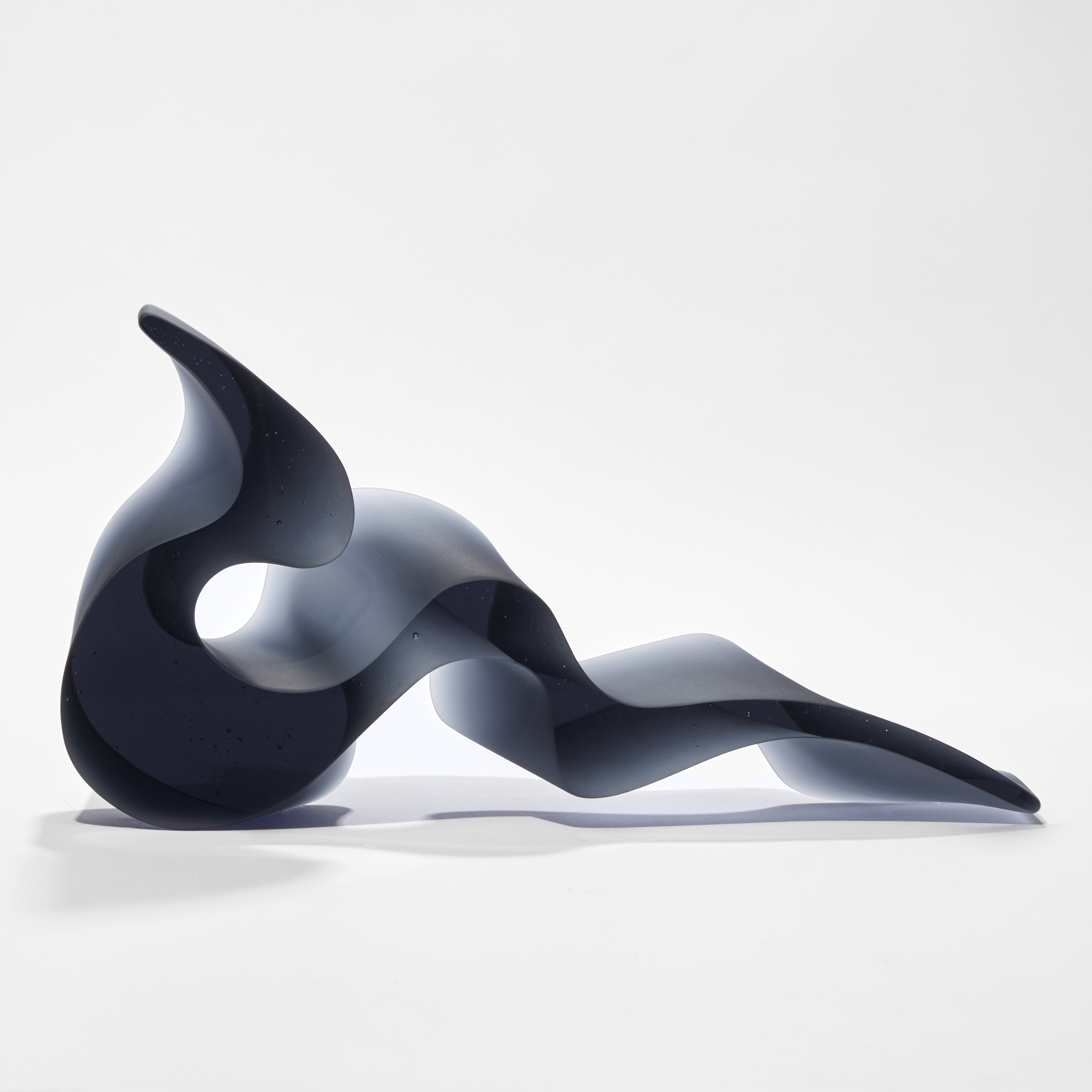 deep steel blue grey abstract simplified snake sculpture with fluid lines and two flat polished sides hand made from glass