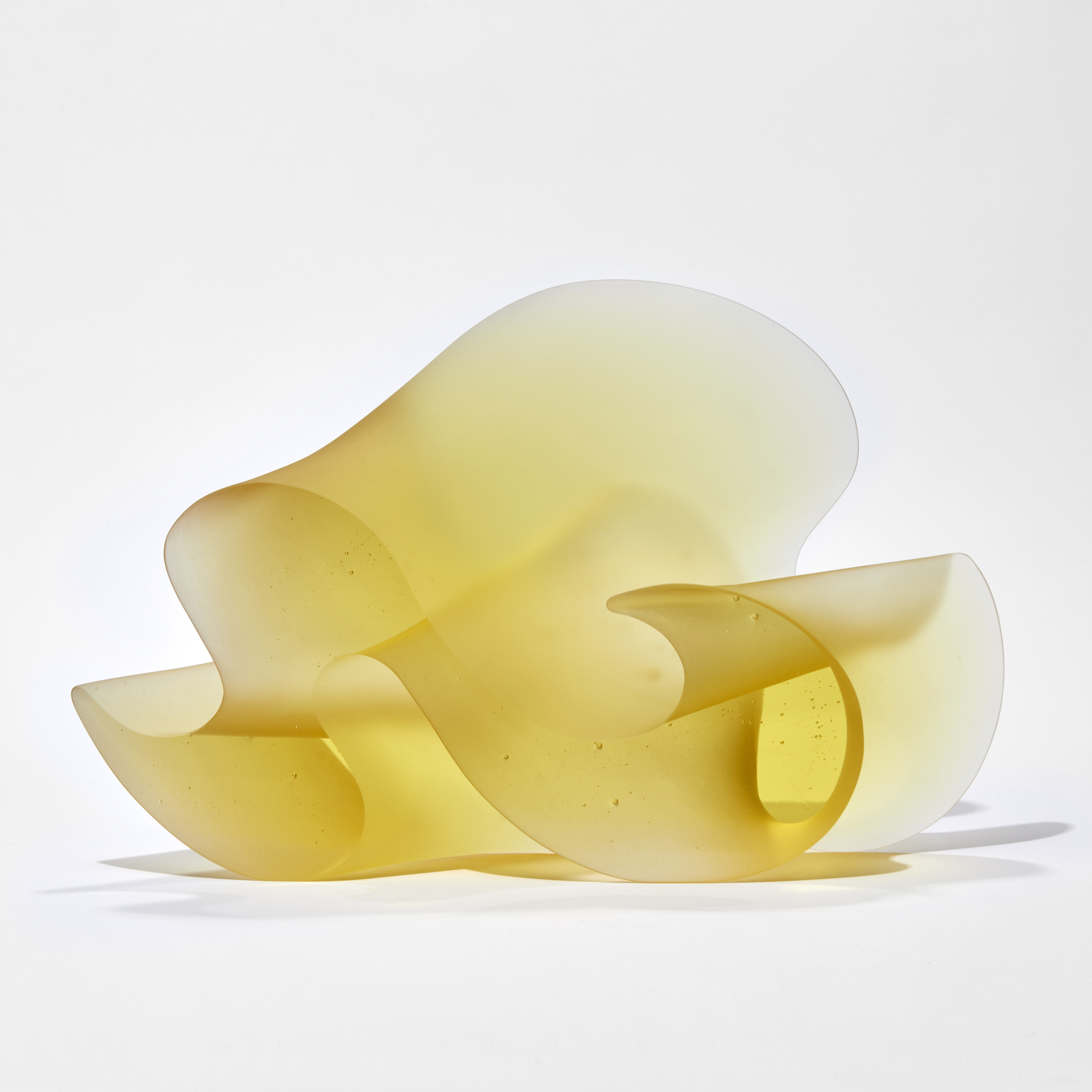 brilliant yellow standing form with two flat shiny sides and sweeping matt curved side with the appearance of a curling thick ribbon or arabic text