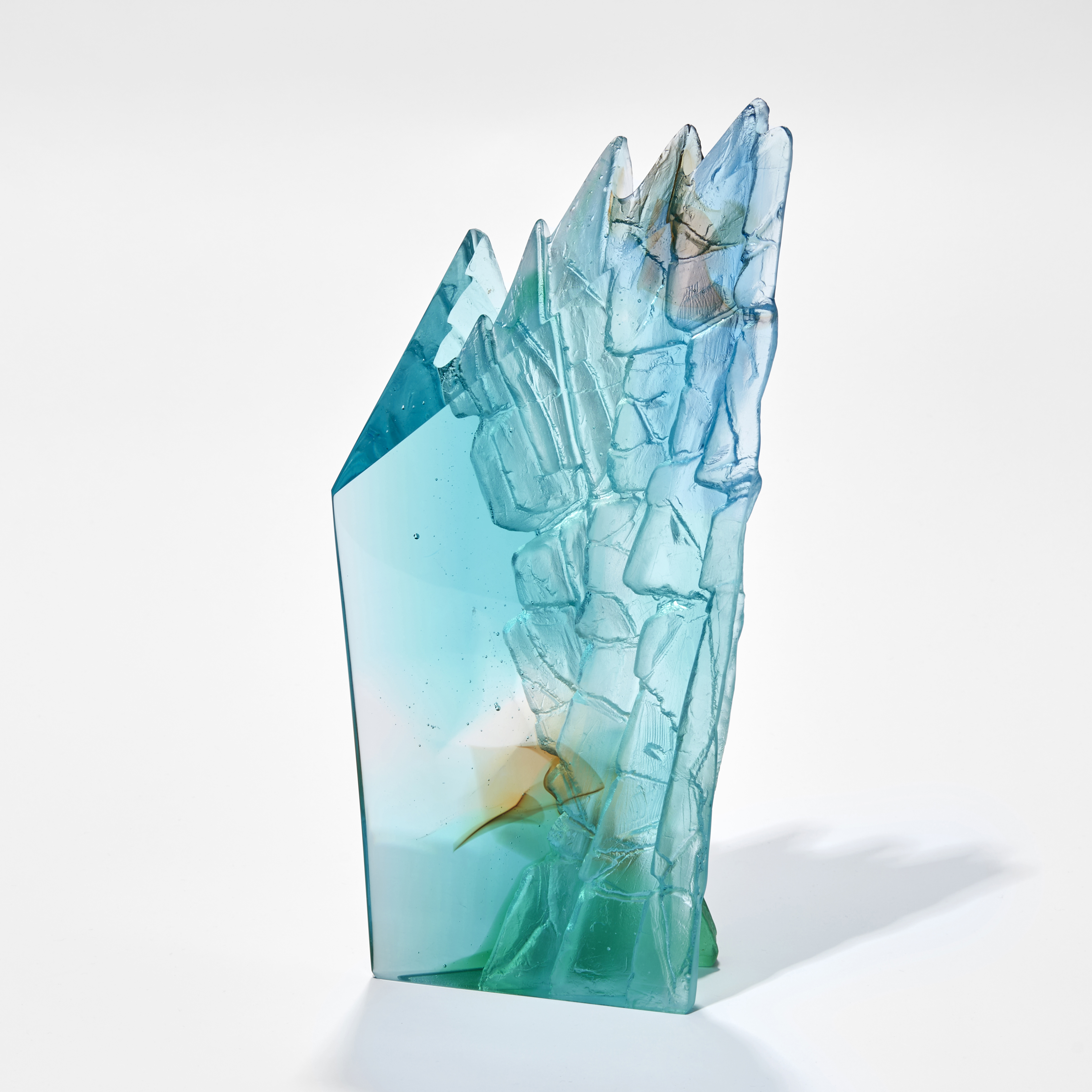cast glass sculpture resembling a cliff face in jade turquoise blue clear and fawn with two polished outer surfaces and two inner highly textured surfaces