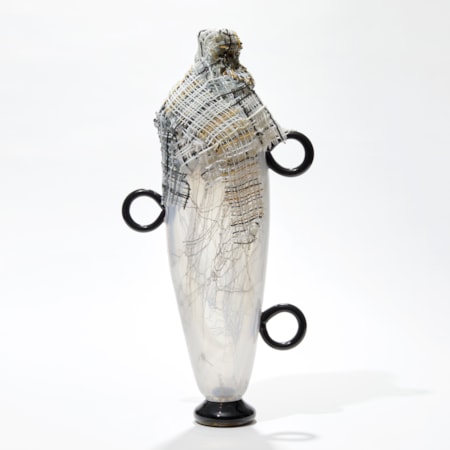 tall opaque white abstract figurative vessel with black ring handles and wrapped in multi-coloured cloth round the opening hand made from glass