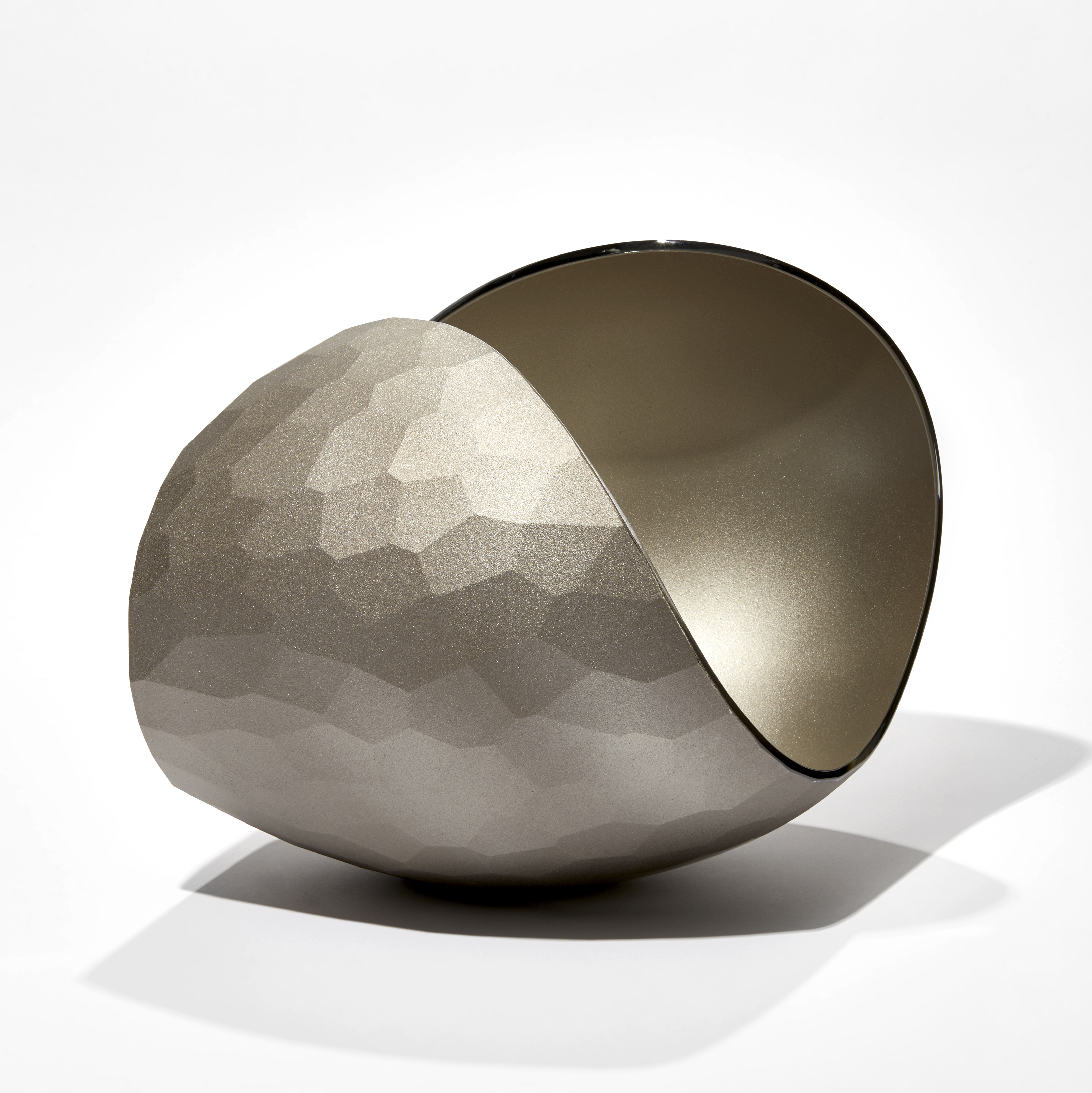 simplified curled shell sculpture with satin bronze finish and single side covered in facetted cuts hand made from blown glass