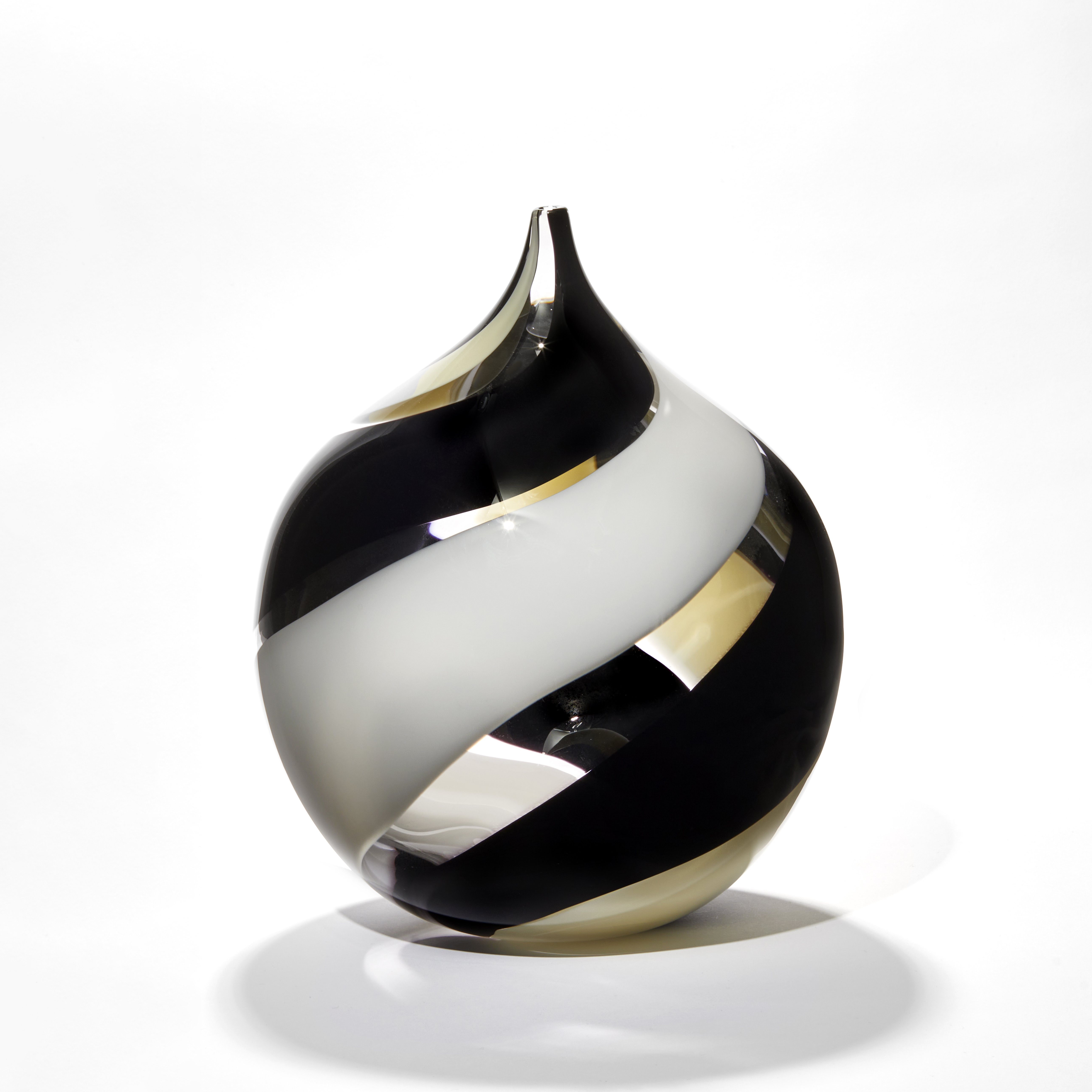 round bottle with pointed neck with fat spiralling stripes in opaque black and opaque white with clear sections hand blown from glass