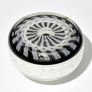 round artwork with white base speckled with black and flat top with embedded swirling ribboned white pattern on black back ground hand made from glass