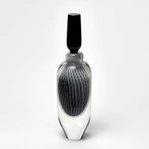 tall elegant round clear bottle with tapered base and long black stopper with fine filigree pattern trapped within hand made from glass