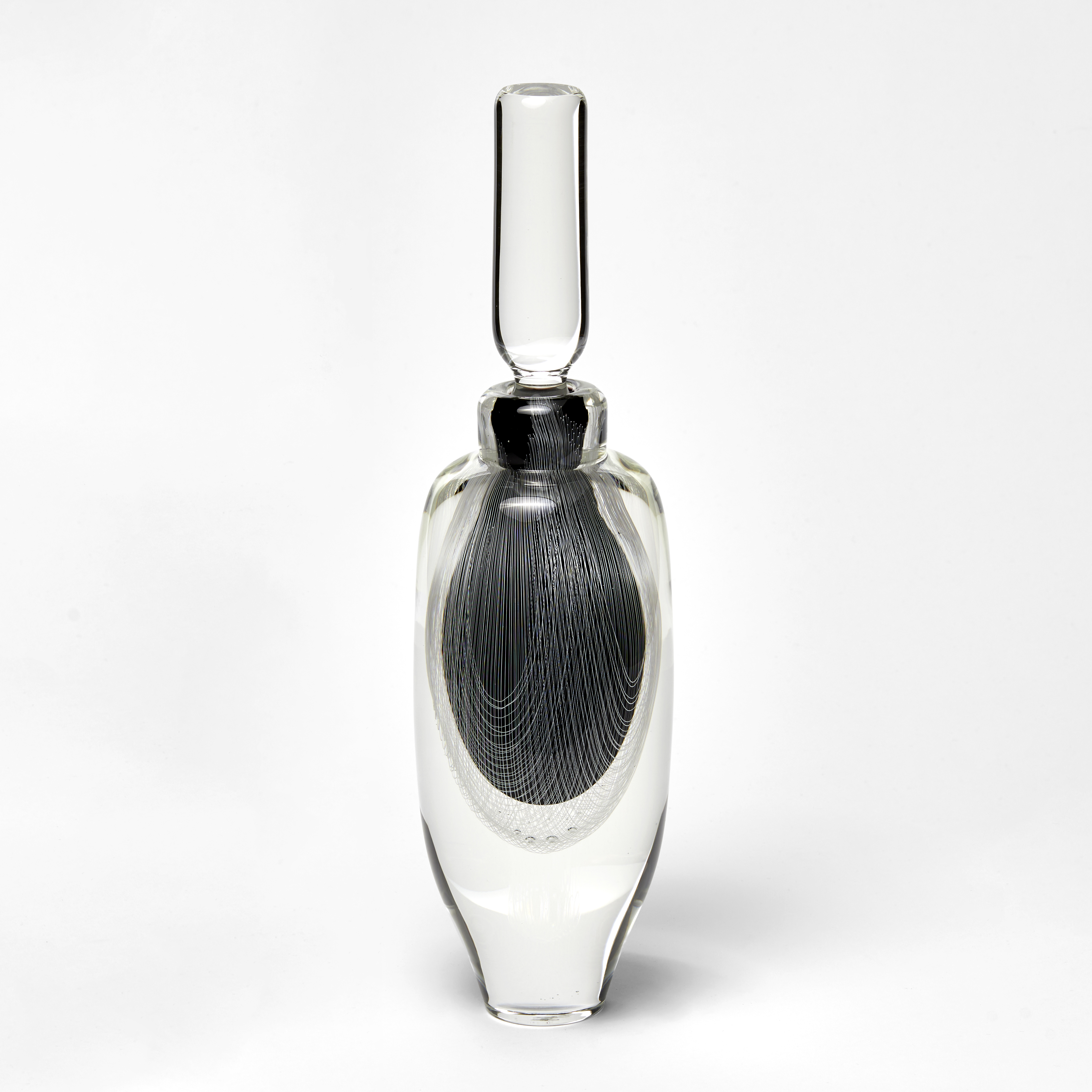 tall clear bottle with stopper with internally trapped fine filigree pattern in white over black hand made from glass