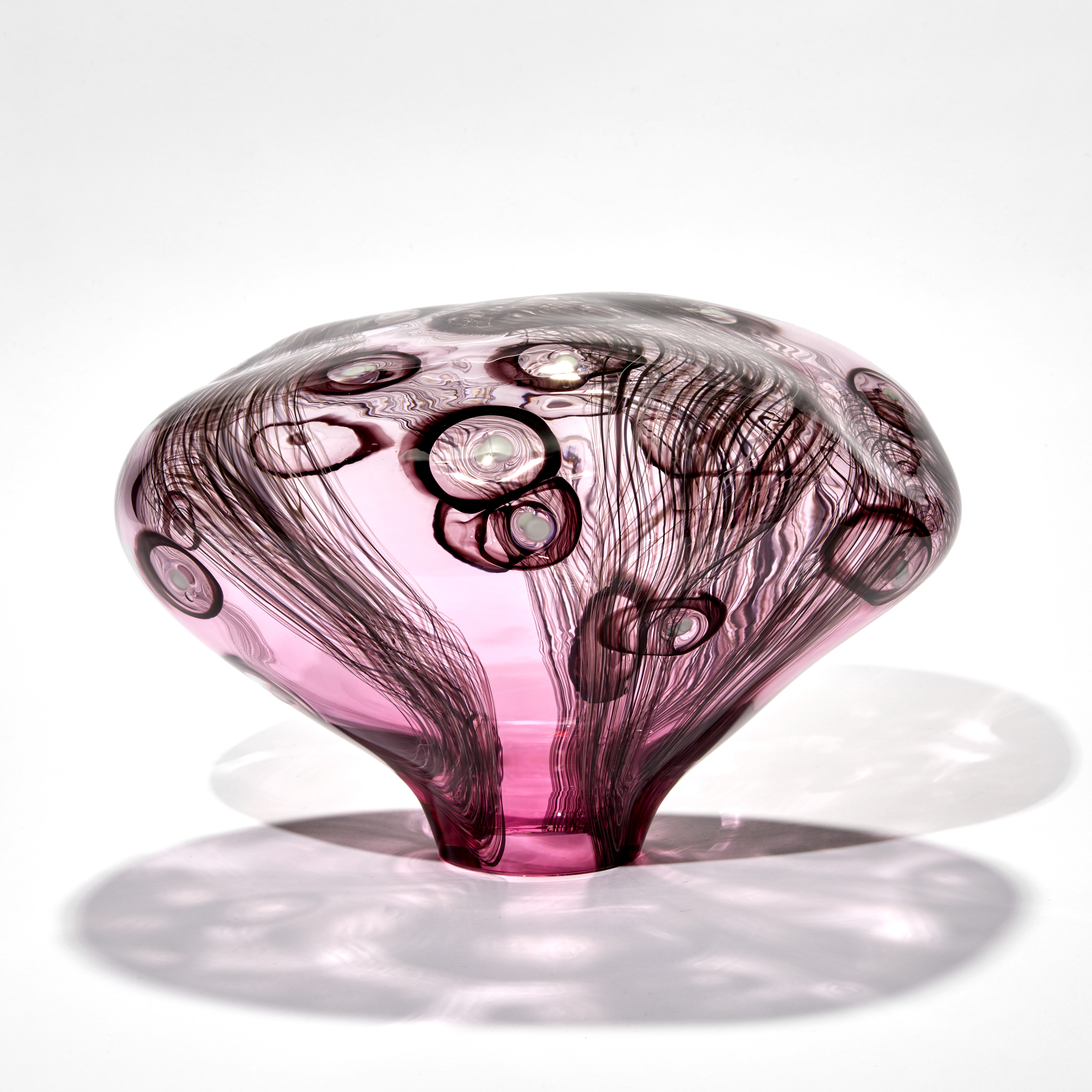 smooth surfaced simplified mushroom shaped sculpture handmade from pink transparent glass with dark aubergine line and circle patterns with white dots