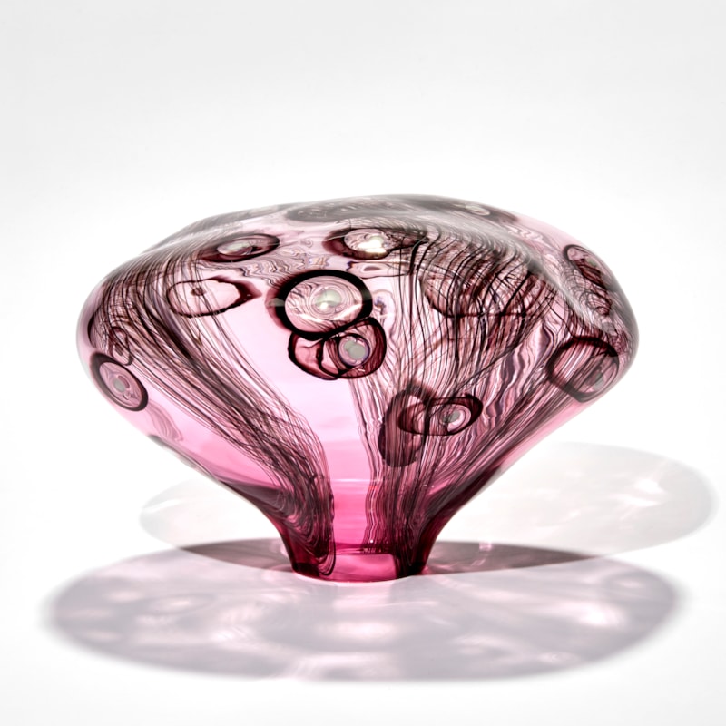 smooth surfaced simplified mushroom shaped sculpture handmade from pink transparent glass with dark aubergine line and circle patterns with white dots