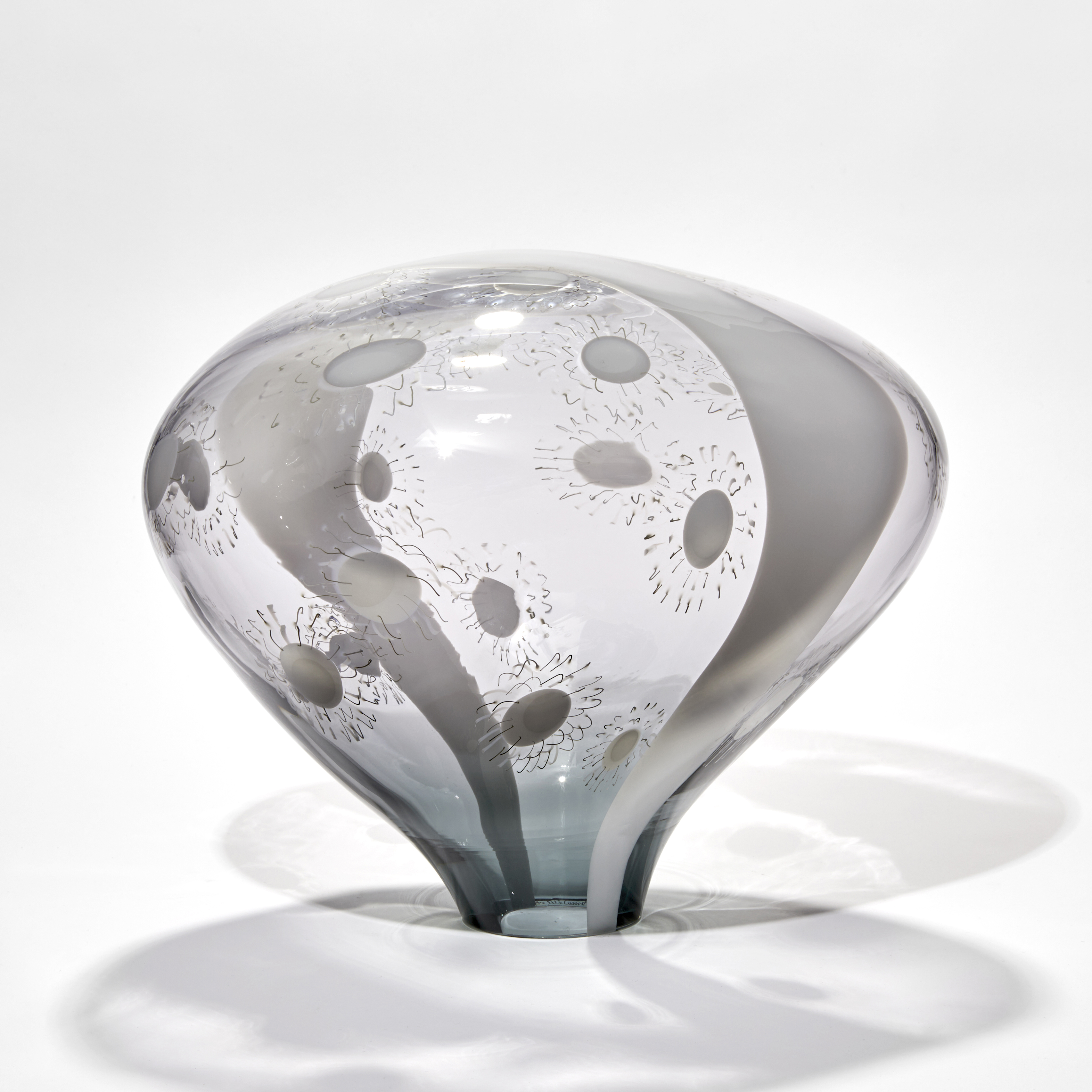transparent grey and opaque white simplified mushroom shaped sculpture with stripe and dot patterns hand made from glass