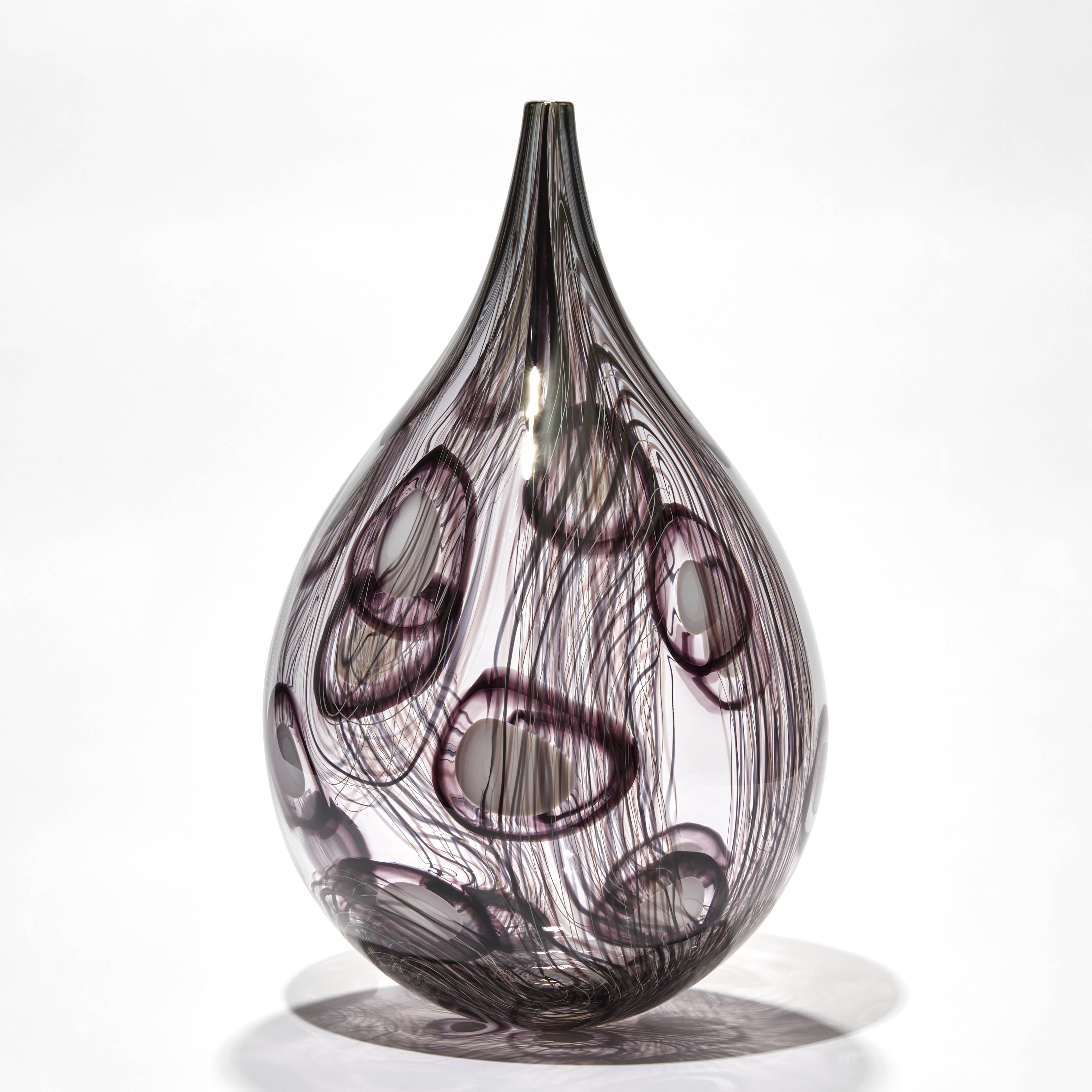 transparent grey and aubergine teardrop shaped vessel with fine lines and abstract circle patterns in dark aubergine handmade from glass