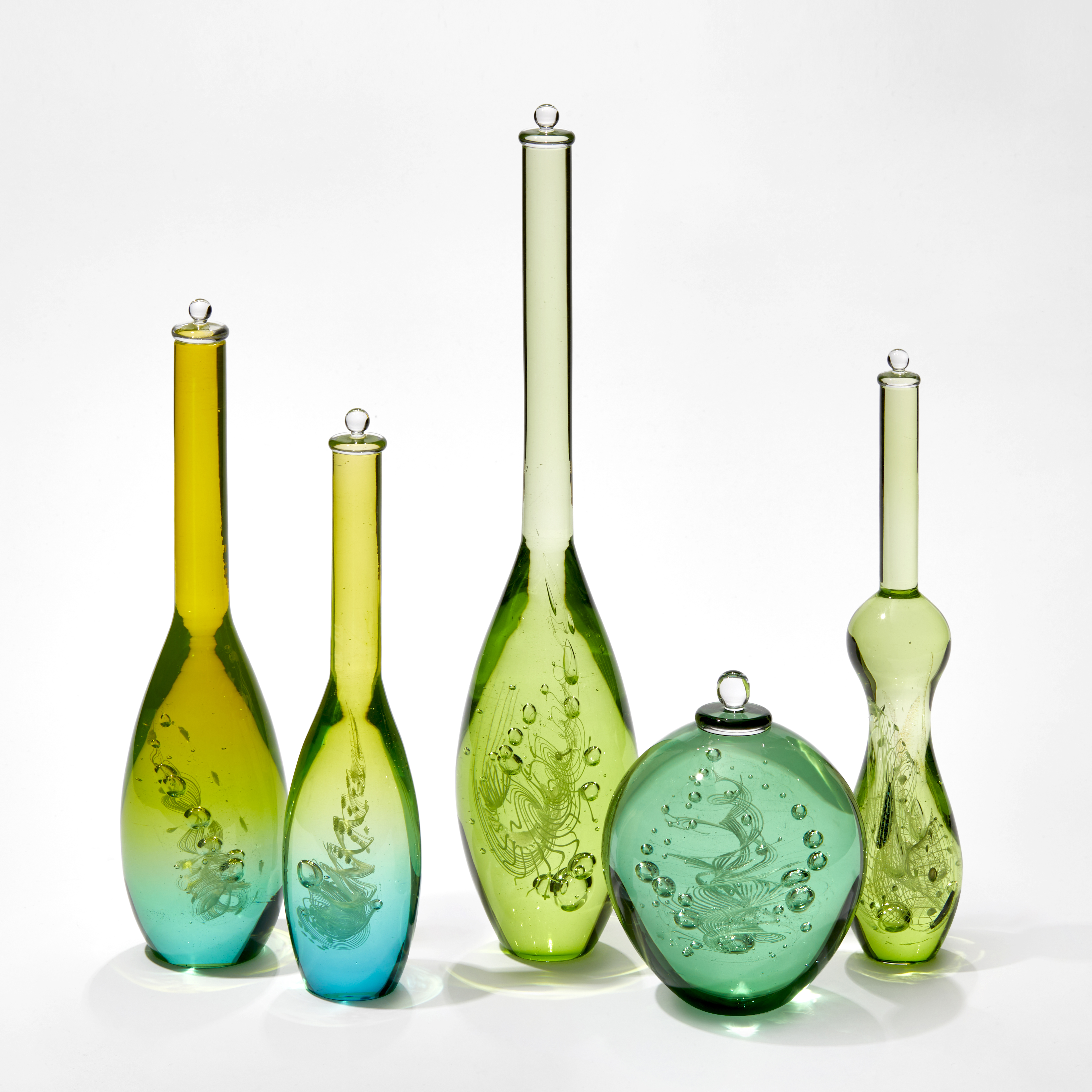 group of five scientific looking bottles in differing shapes in green and turquoise each contacting a helix spiral of inner detail and trapped bubbles