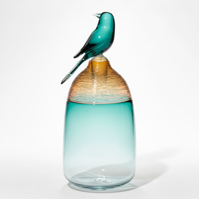 transparent fading jade green jar with amber textured top third section and stopper with a jade green sculpted bird attached hand made from glass