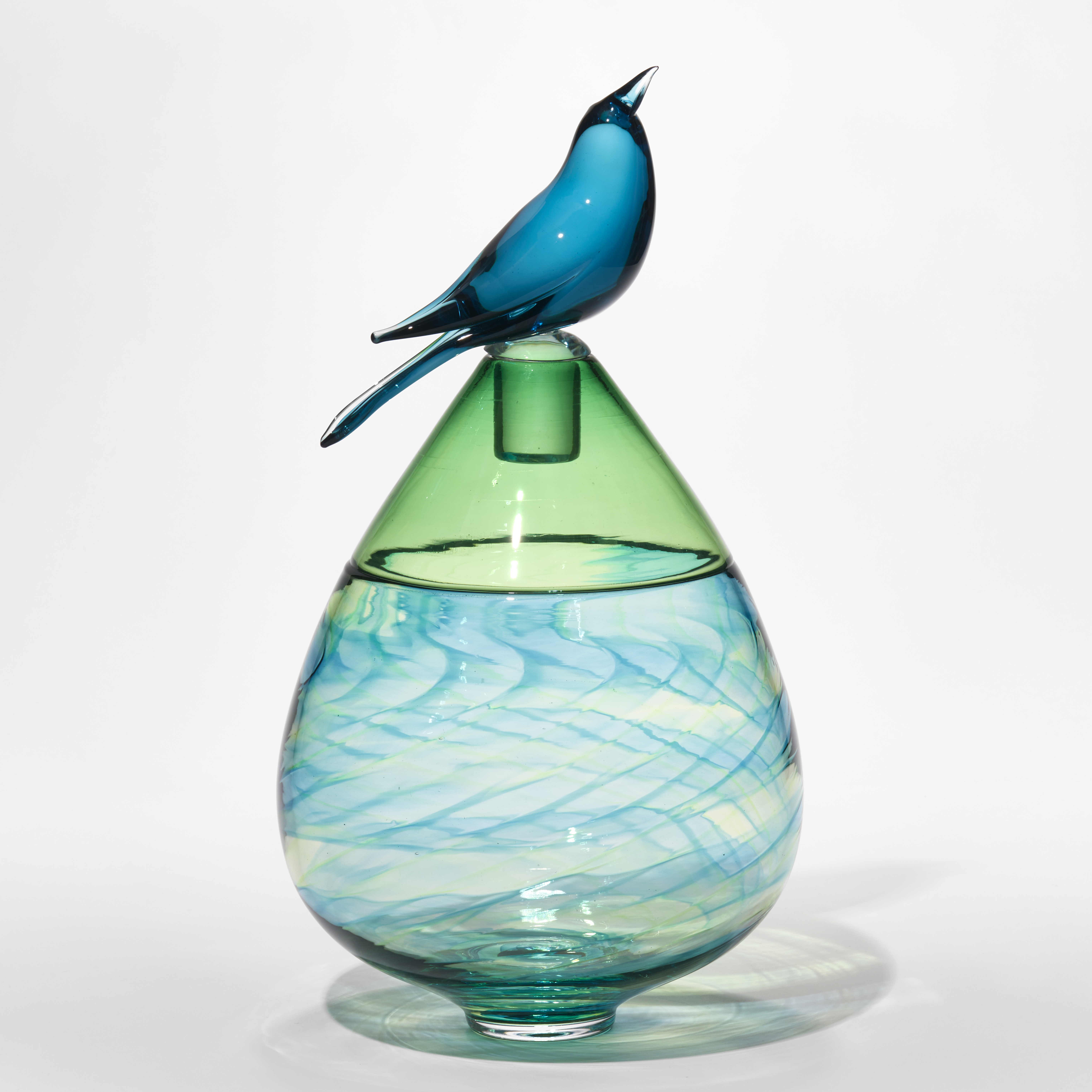 lime green and blue teardrop shaped bottle with swirling pattern and upper top section in transparent green with stopper and blue bird perched on top hand made from glass